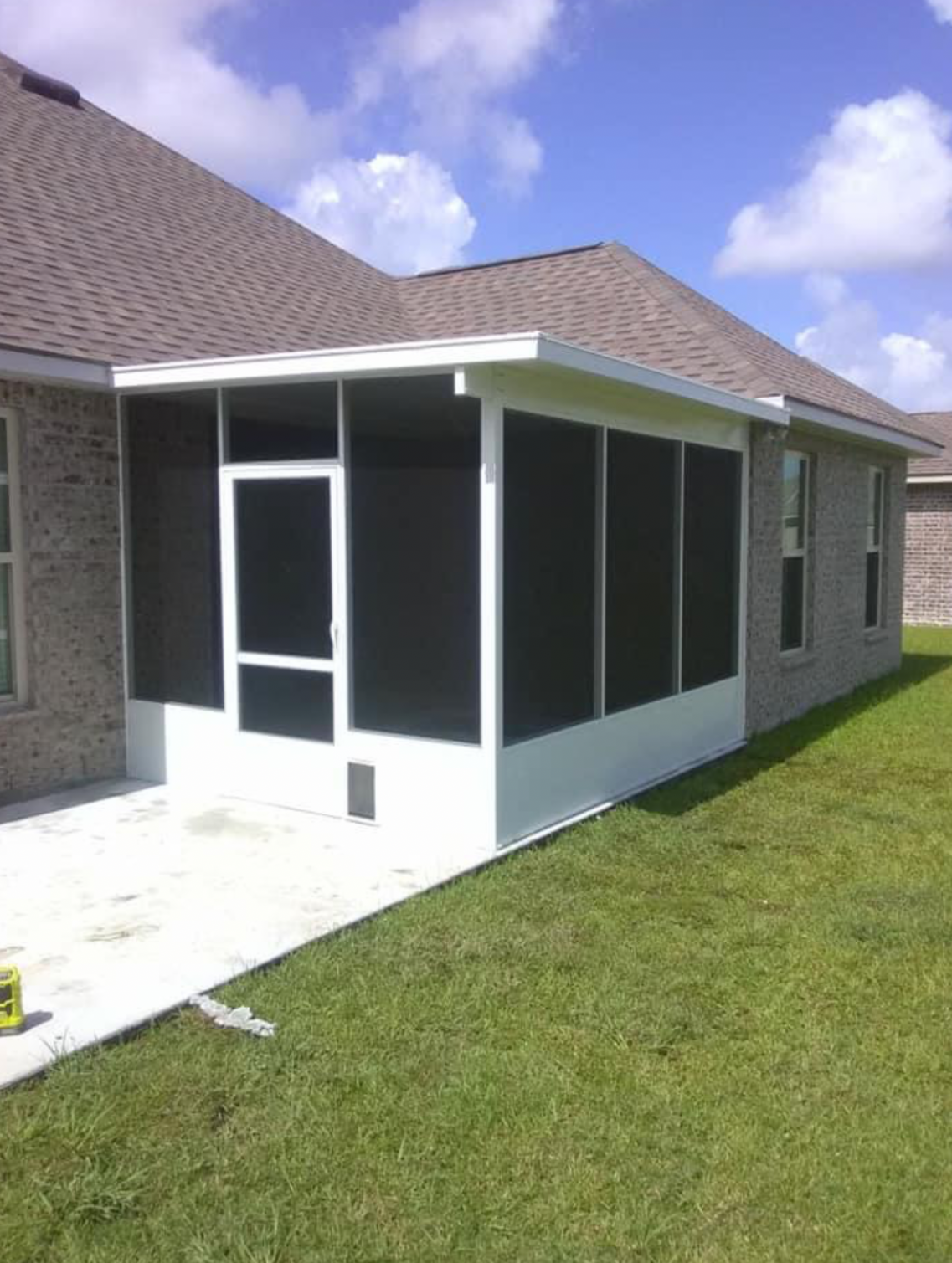 A screened in porch on the side of a house.