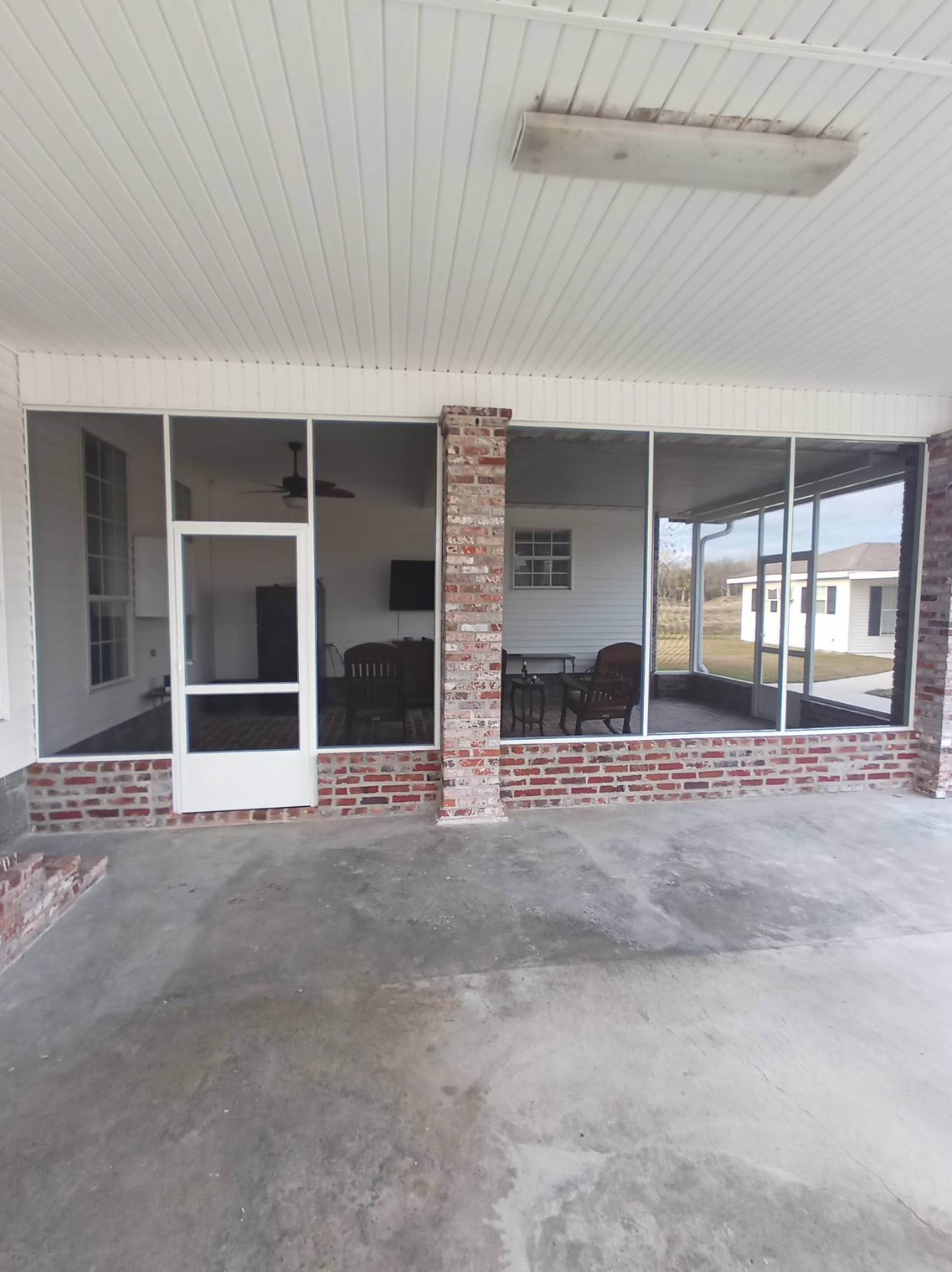 A screened in porch with a brick wall and a ceiling fan.