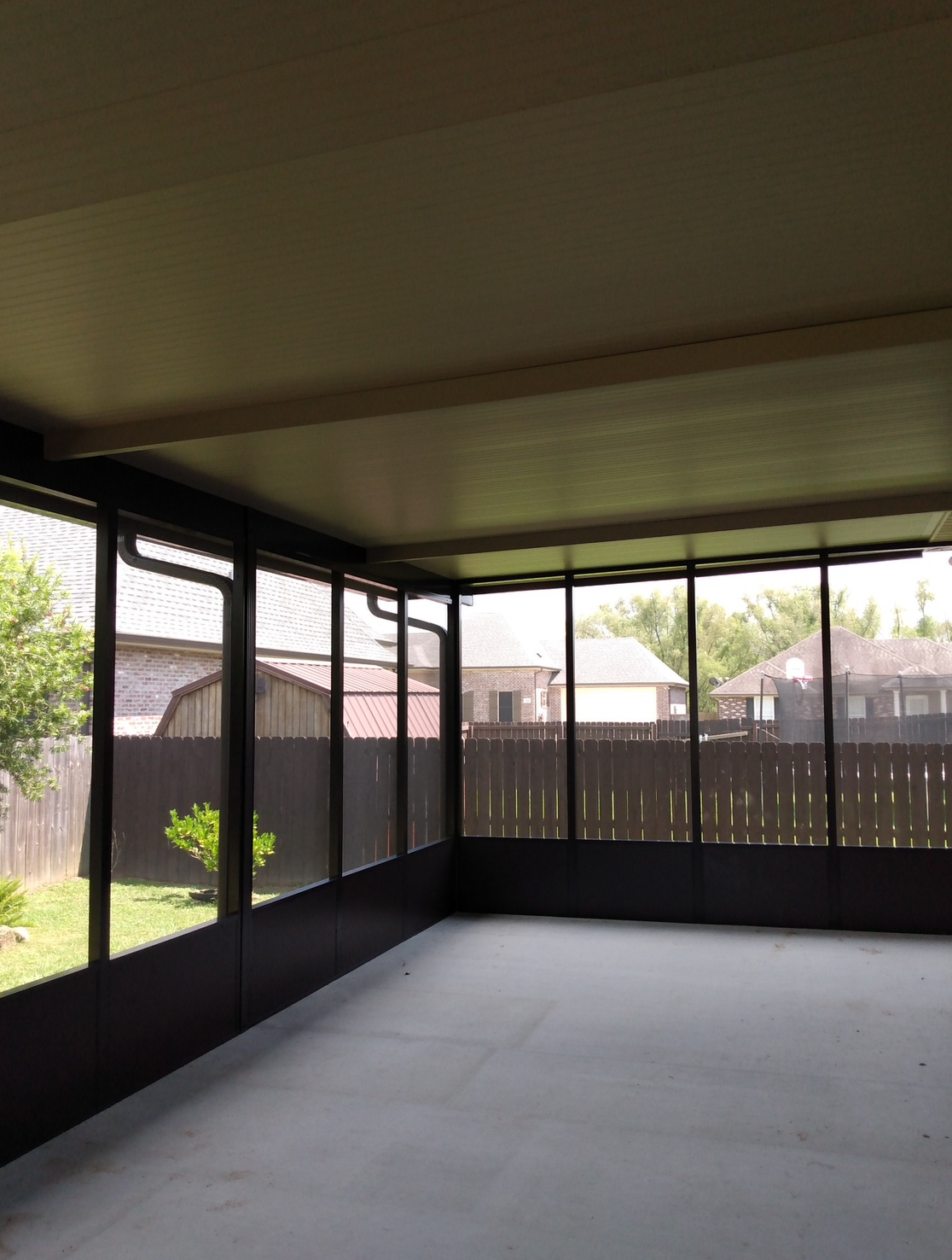 A screened in porch with a fence in the background.