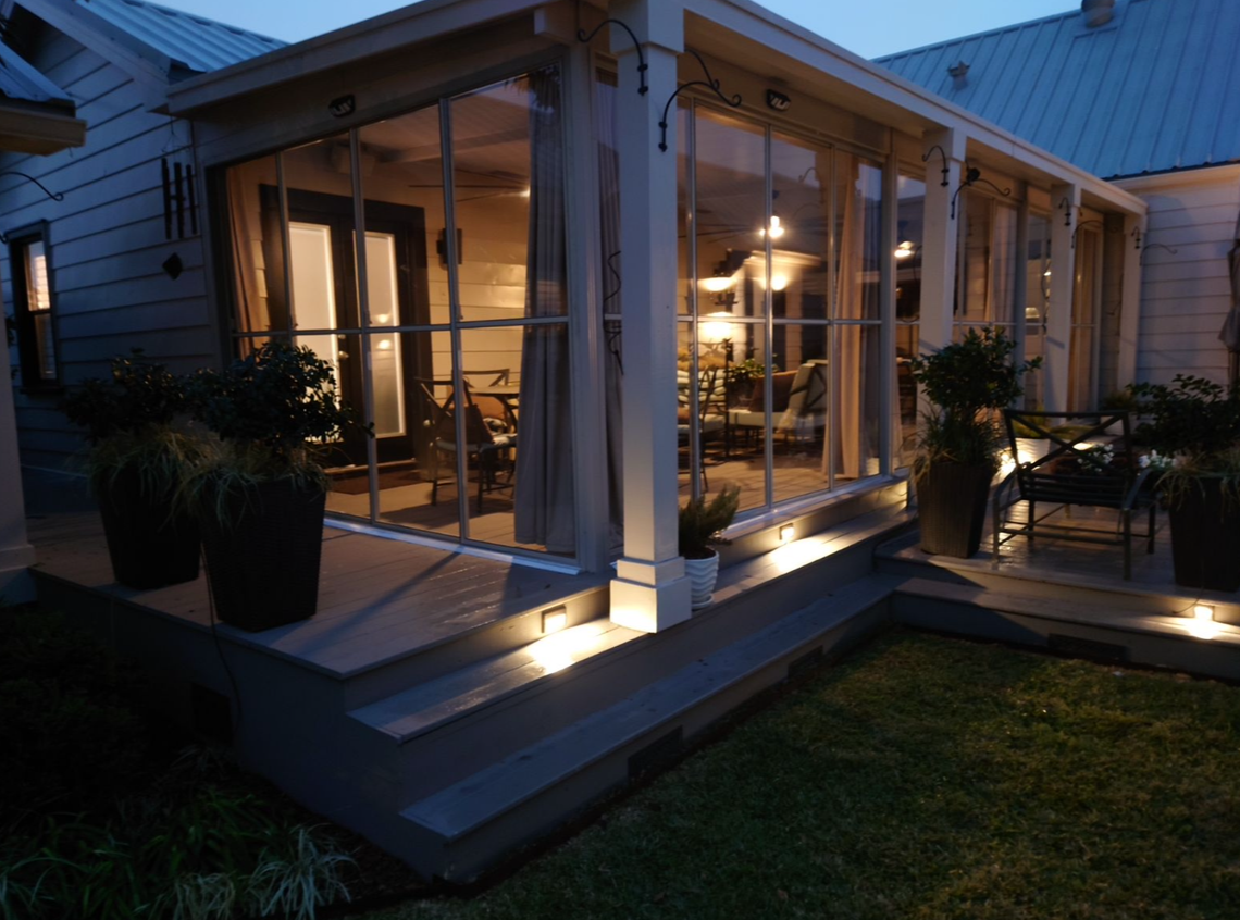 A house with a screened in porch at night.