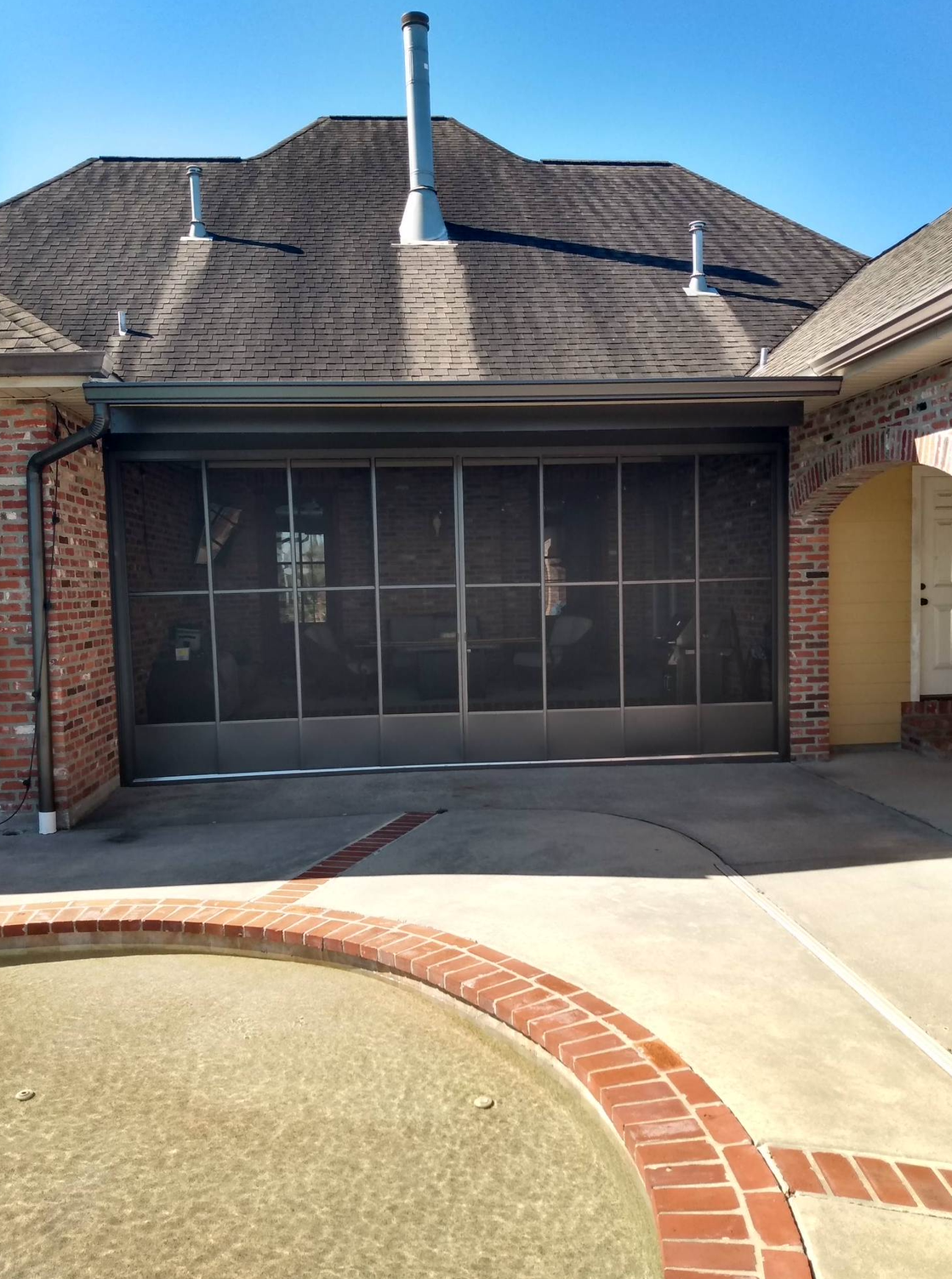 A screened in garage door is sitting in front of a brick house.