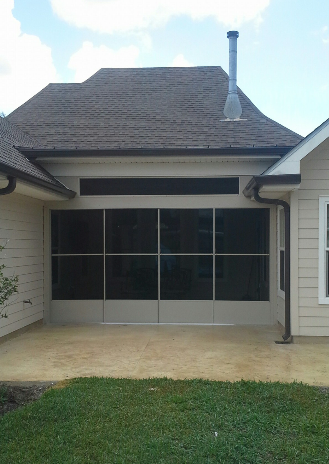 A house with a screened in porch and a chimney on the roof.