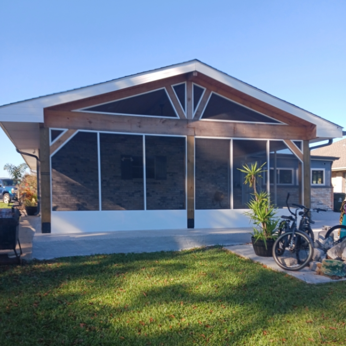A house with a screened in porch and bikes parked in front of it.