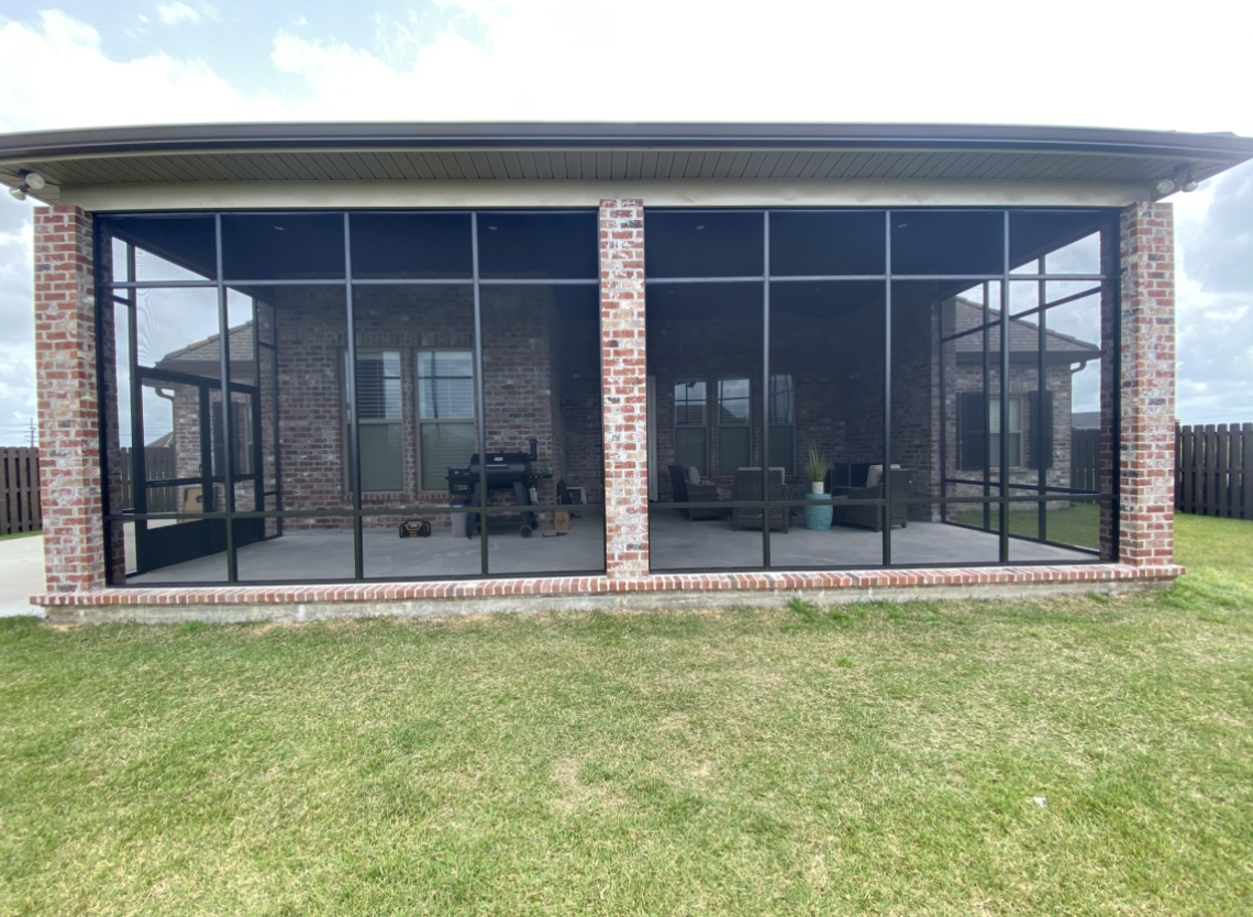 There is a screened in porch in the backyard of a house.