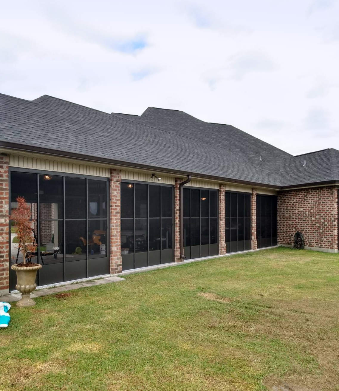 A brick house with a lot of windows and a lawn in front of it.