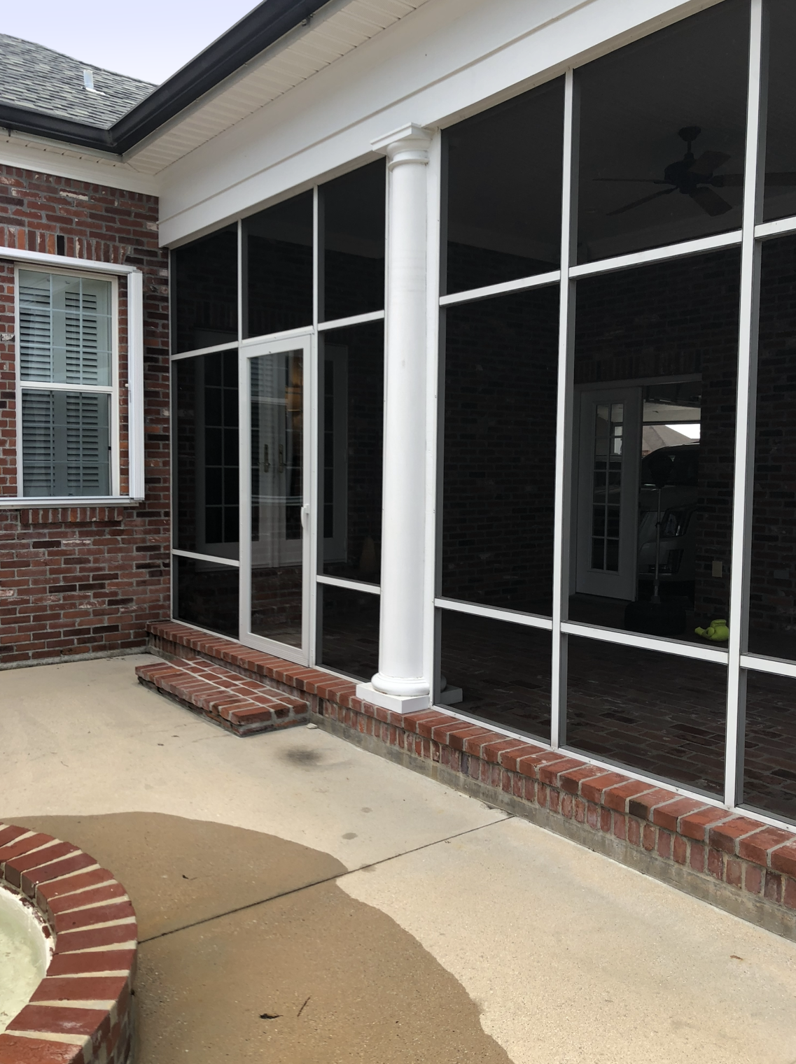 A screened in porch with a brick wall and a sliding glass door.