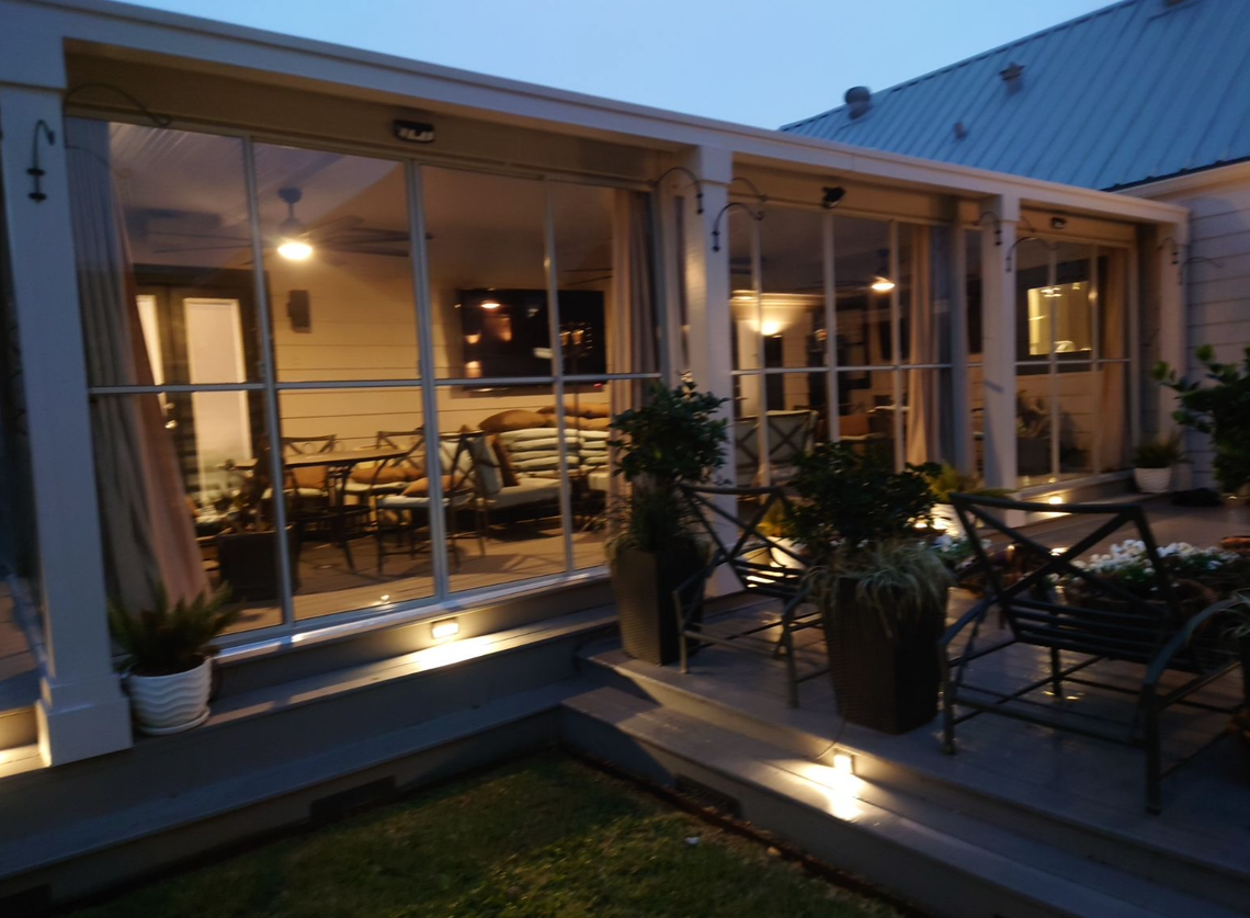 A porch with a lot of windows is lit up at night.