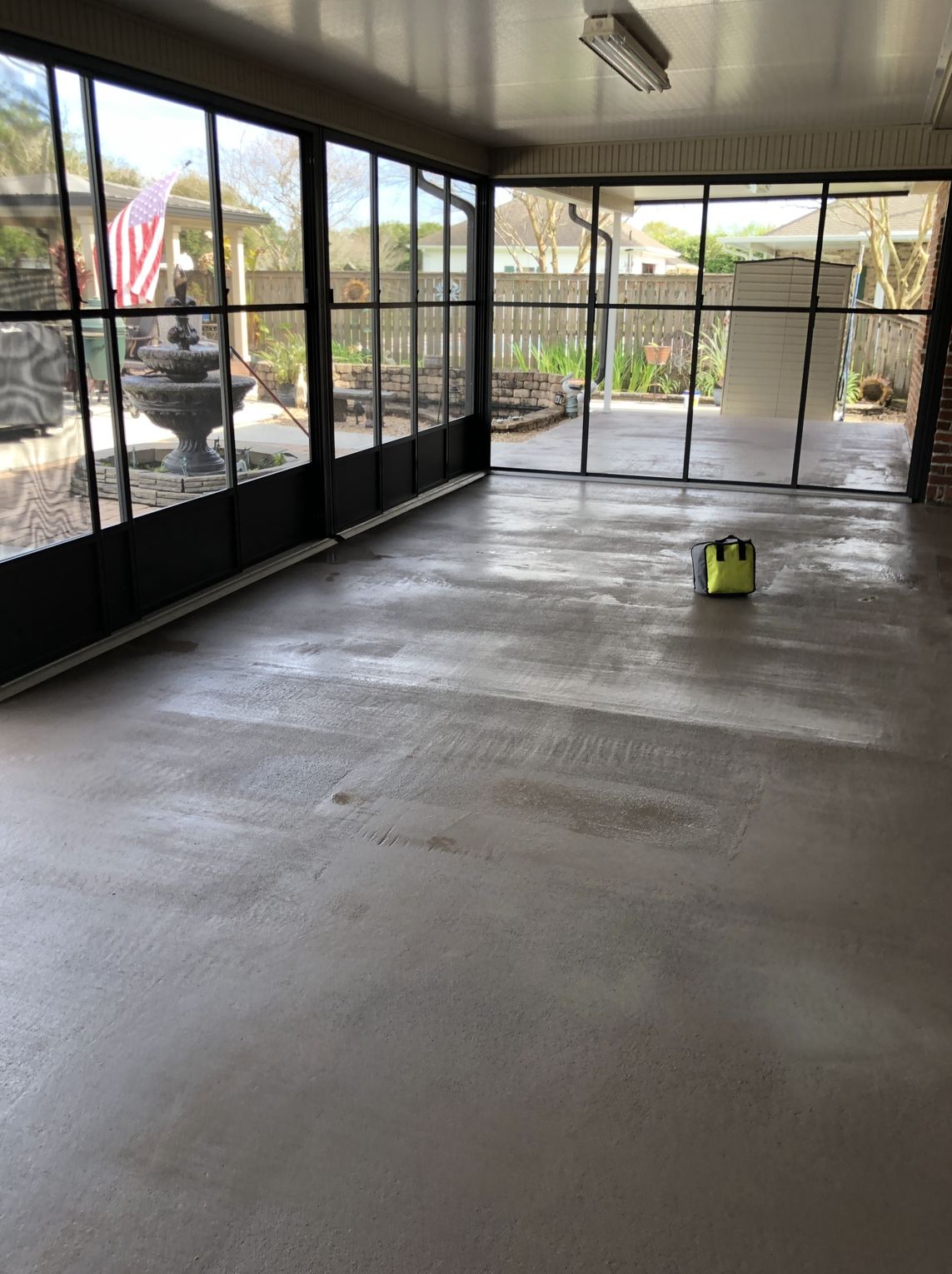 An empty room with a lot of windows and a yellow bag on the floor.