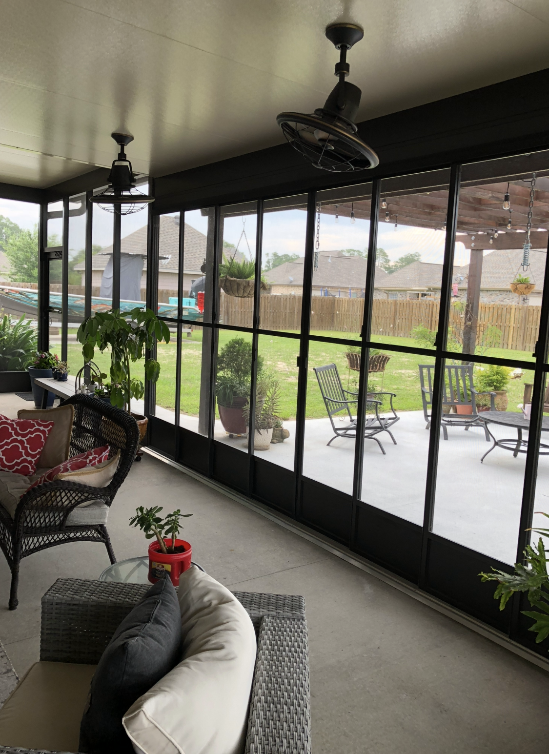 A screened in porch with a lot of windows and a ceiling fan.