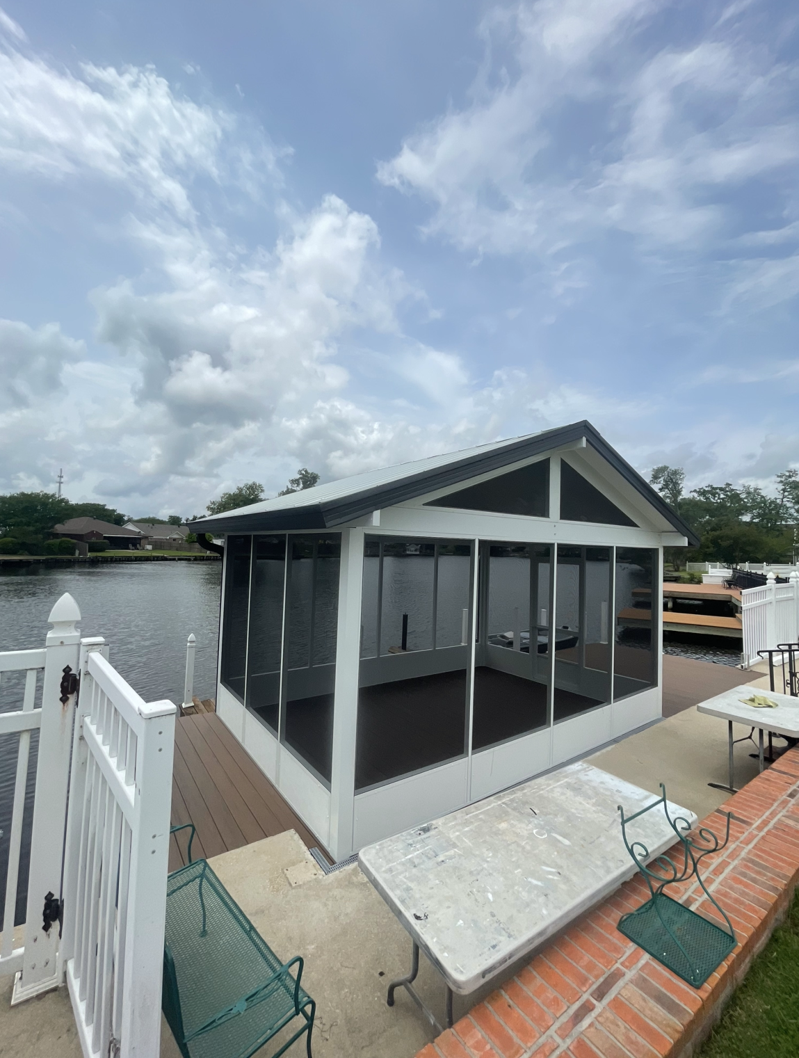 A screened in porch with a table and chairs next to a body of water.
