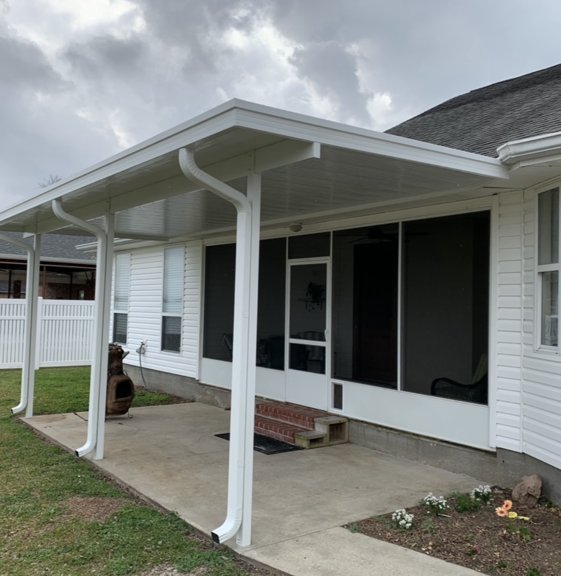 A white house with a screened in porch on a cloudy day.