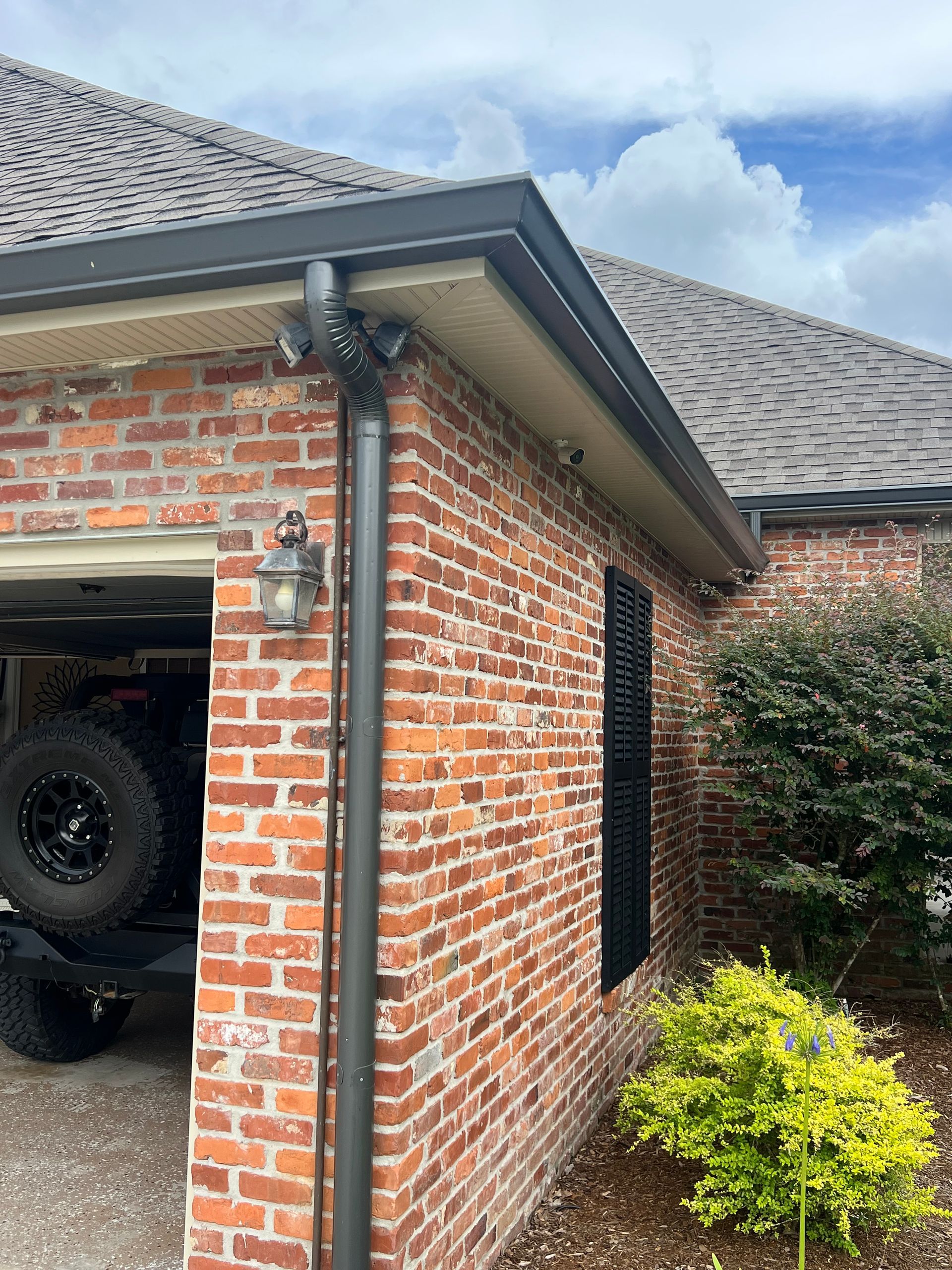 A brick house with a car parked in the garage.