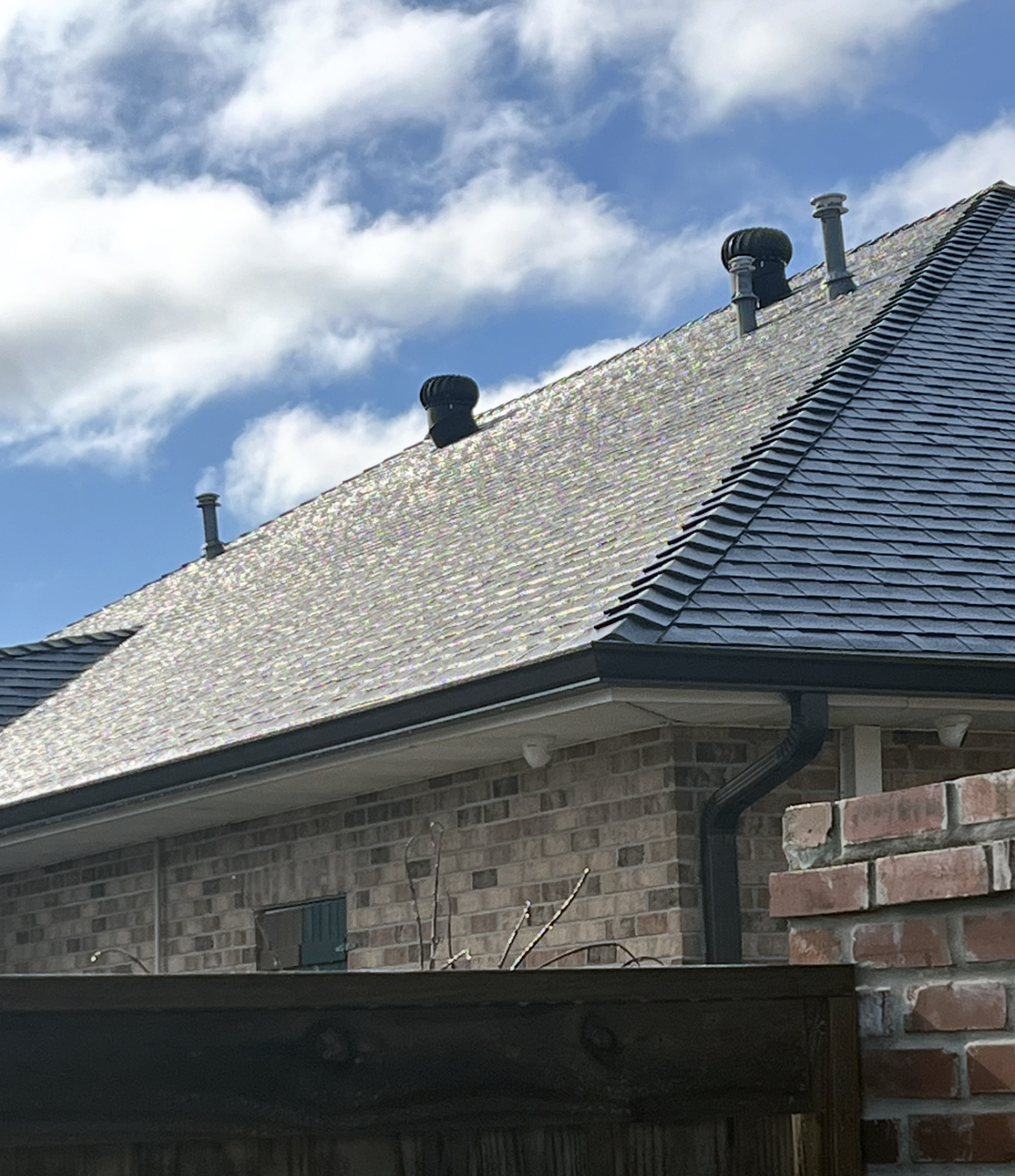 The roof of a brick house with a blue sky in the background.