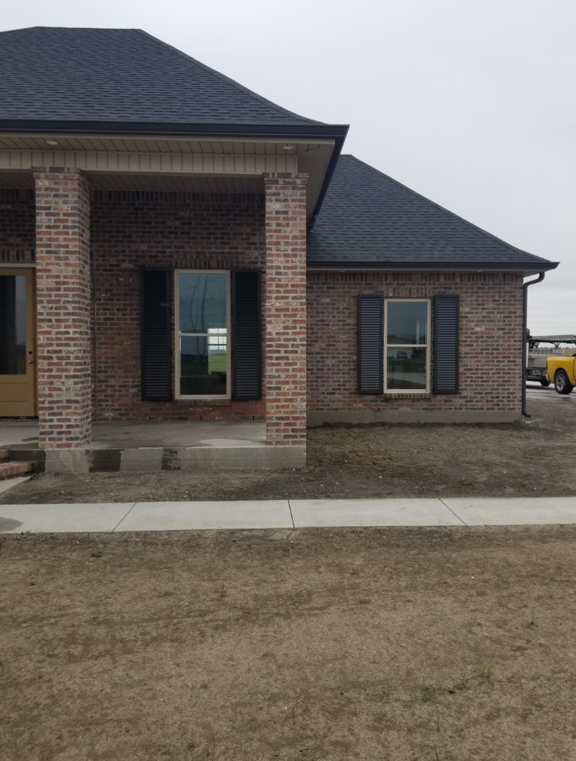A brick house with black shutters on the windows.
