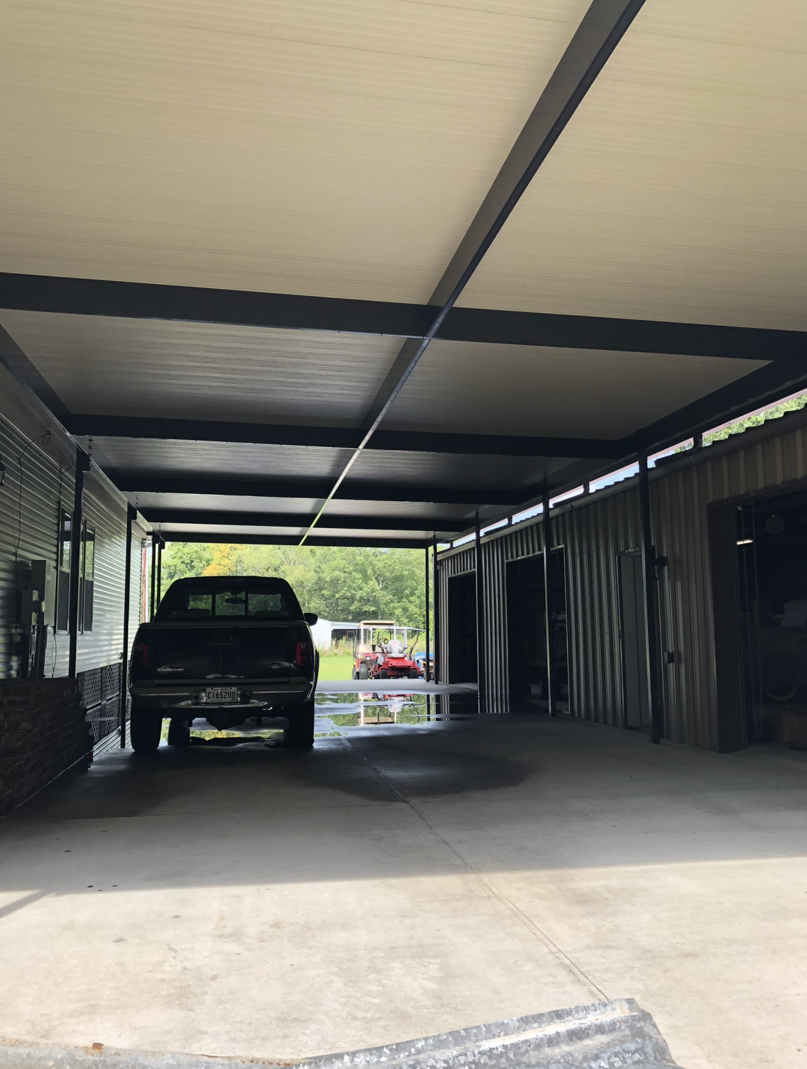 A truck is parked under a canopy in a parking lot.