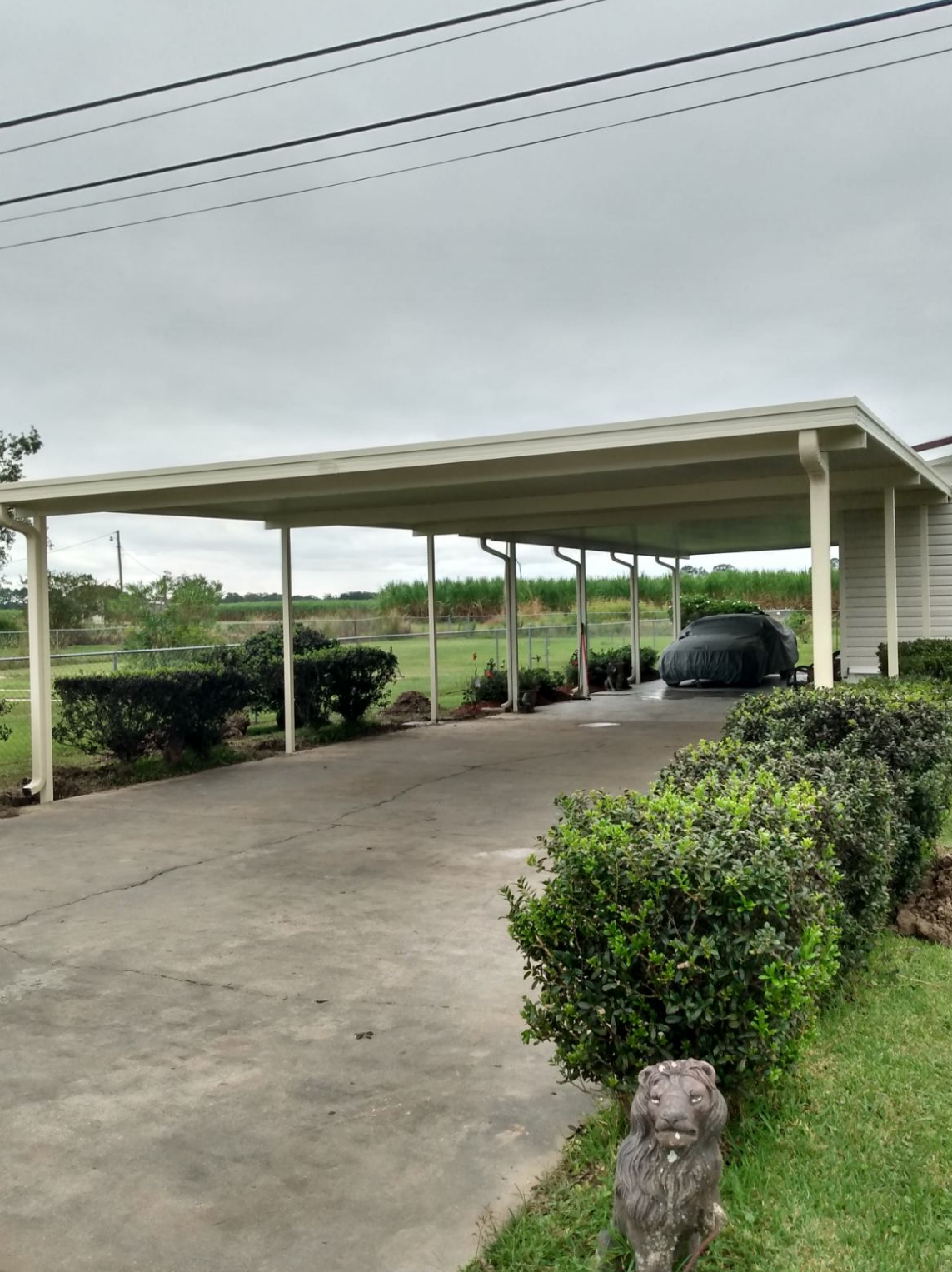 A car is parked under a carport on a cloudy day.