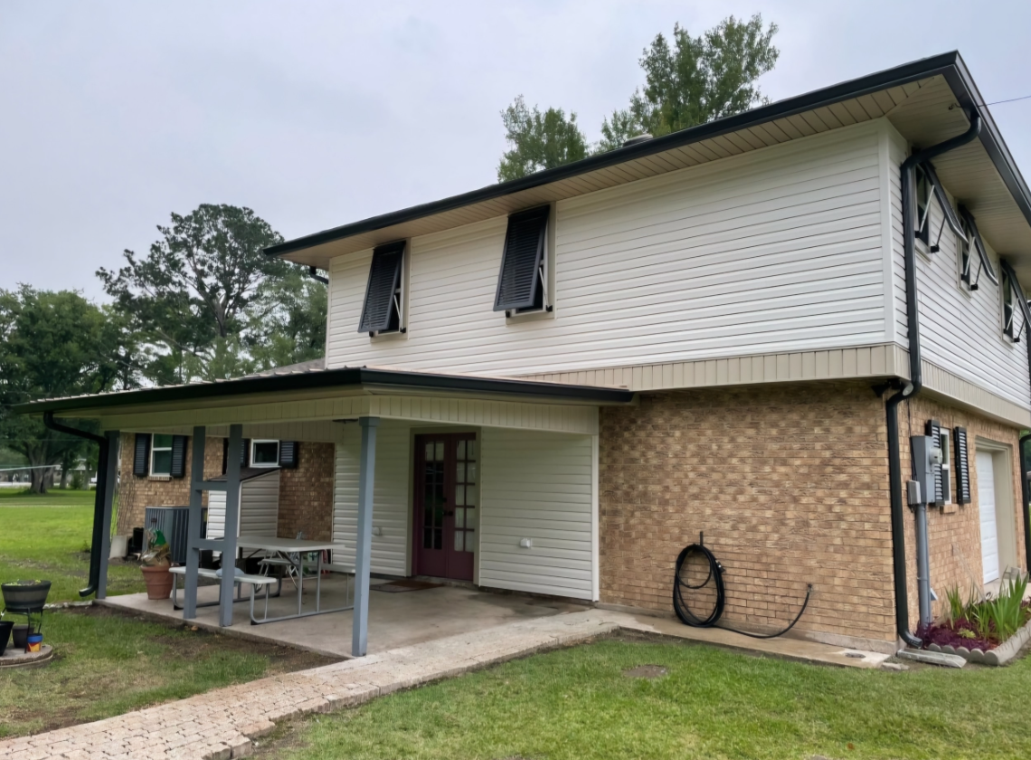 A house with a porch and a lawn in front of it.