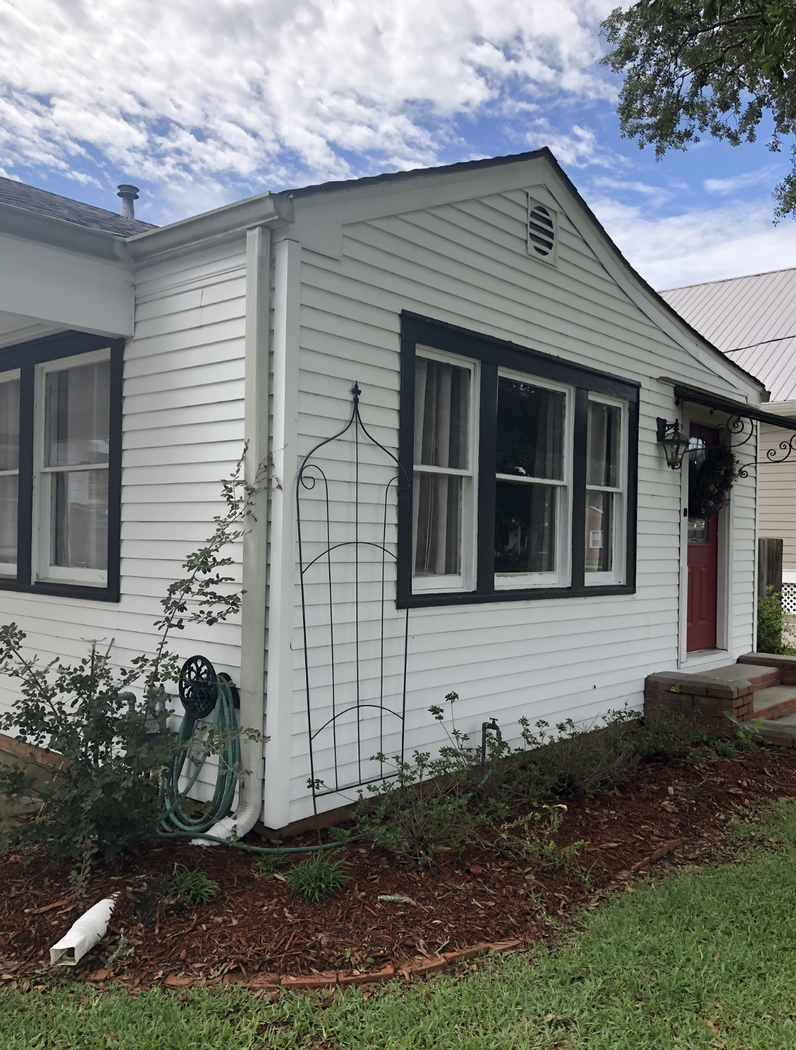 A white house with a red door and a hose in front of it.