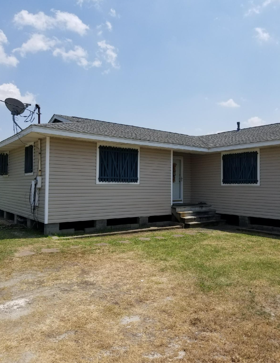 A house with a satellite dish on the roof is sitting on top of a lush green field.