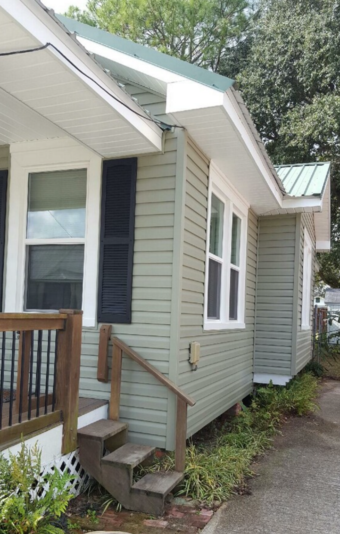 A small house with a green roof and stairs.