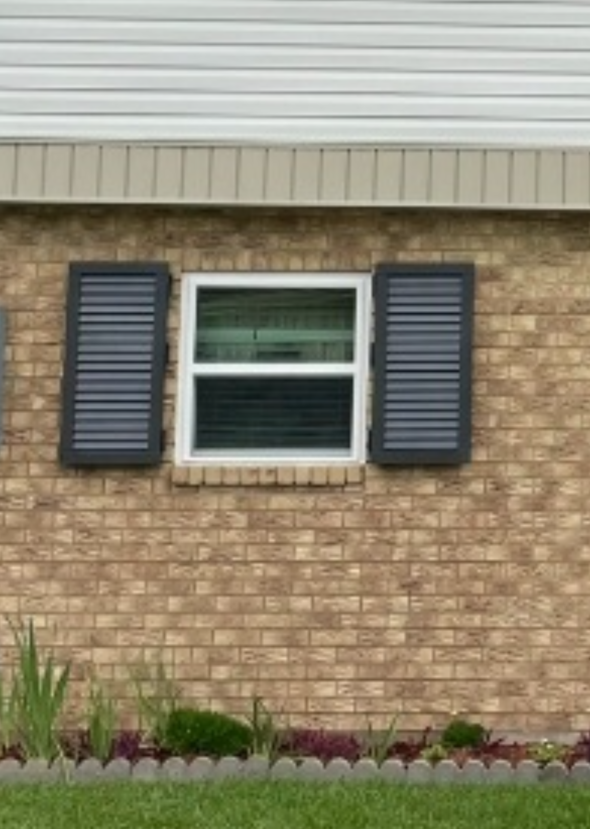 A white house with a brick wall and a lot of windows.