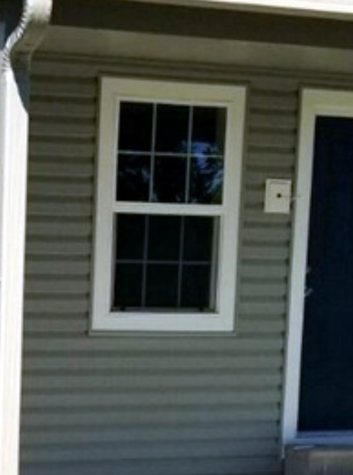 A brick wall with three windows on it.