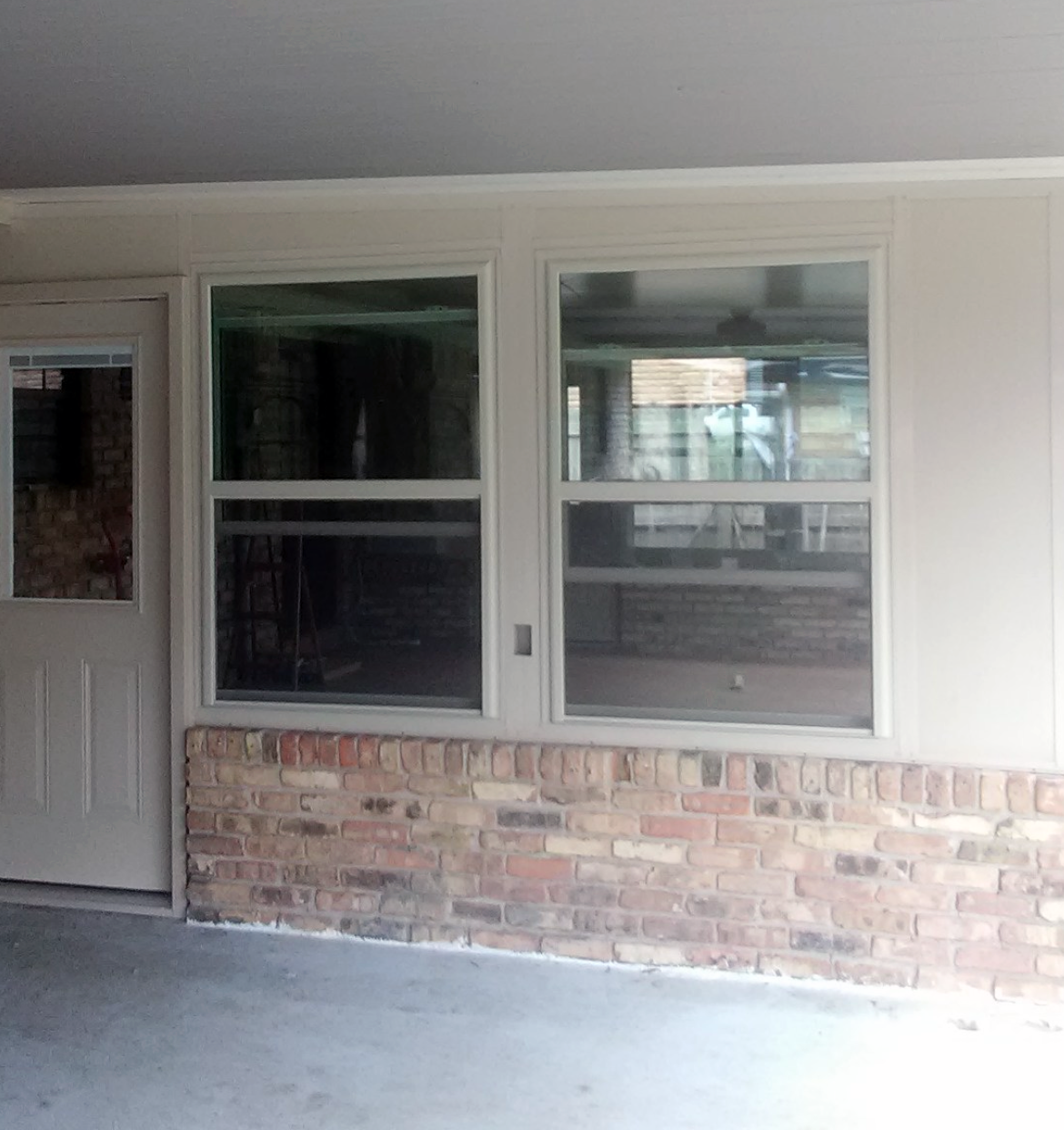 A brick house with a window and black shutters.