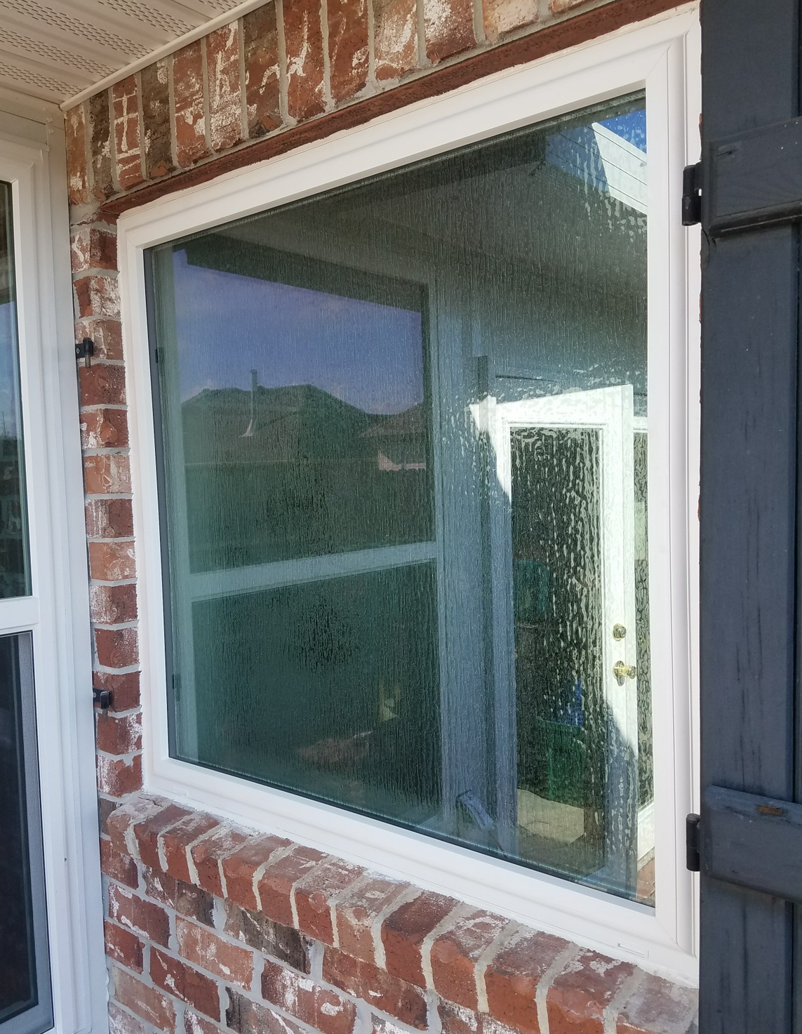 A porch with a grill and a lot of windows.