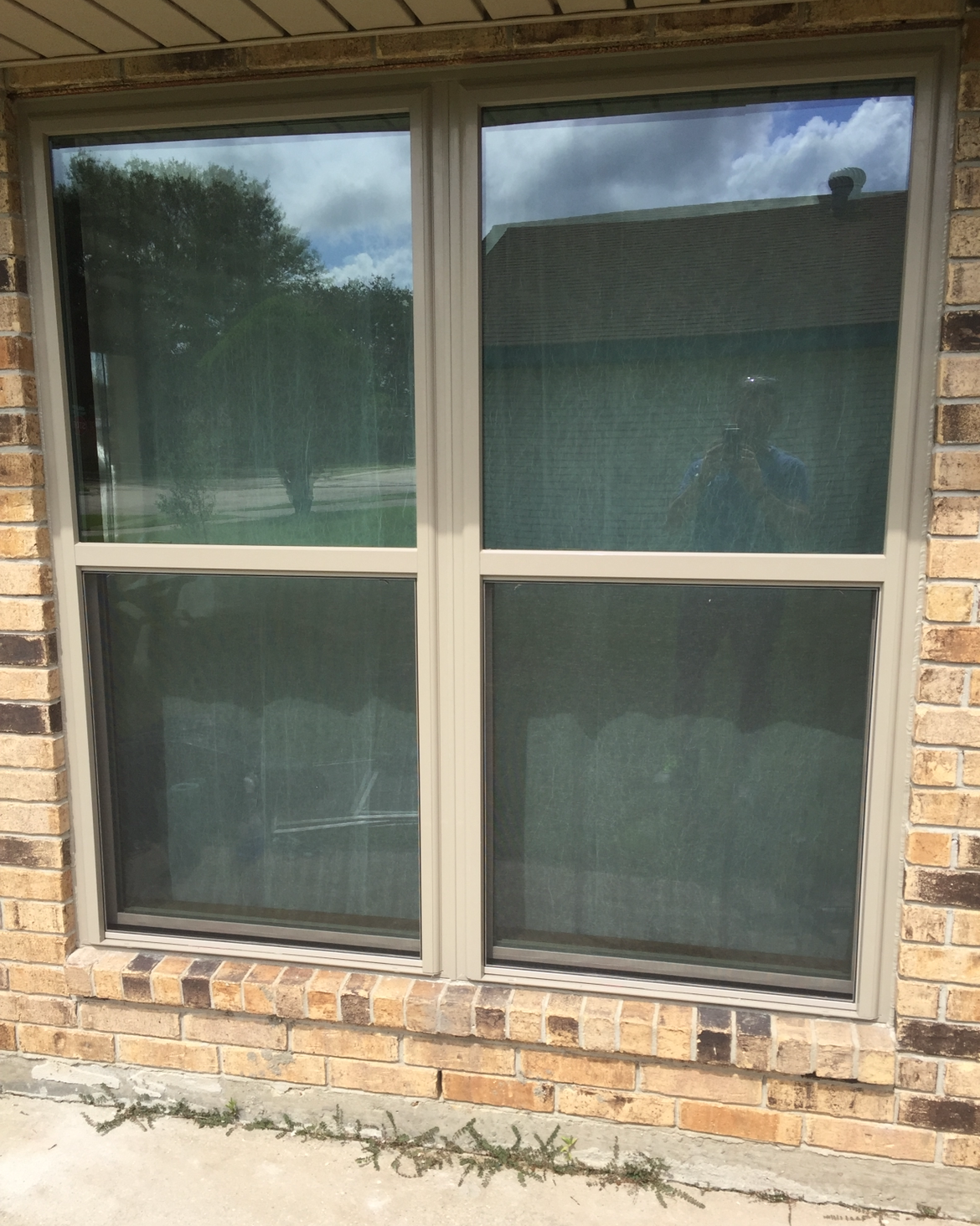 A brick wall with a window and black shutters on it.