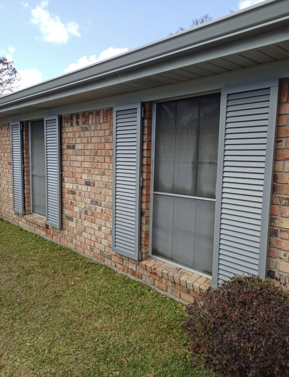A brick house with gray shutters on the windows.