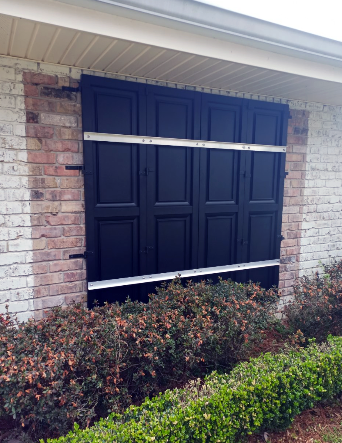 A black garage door is attached to a brick wall.