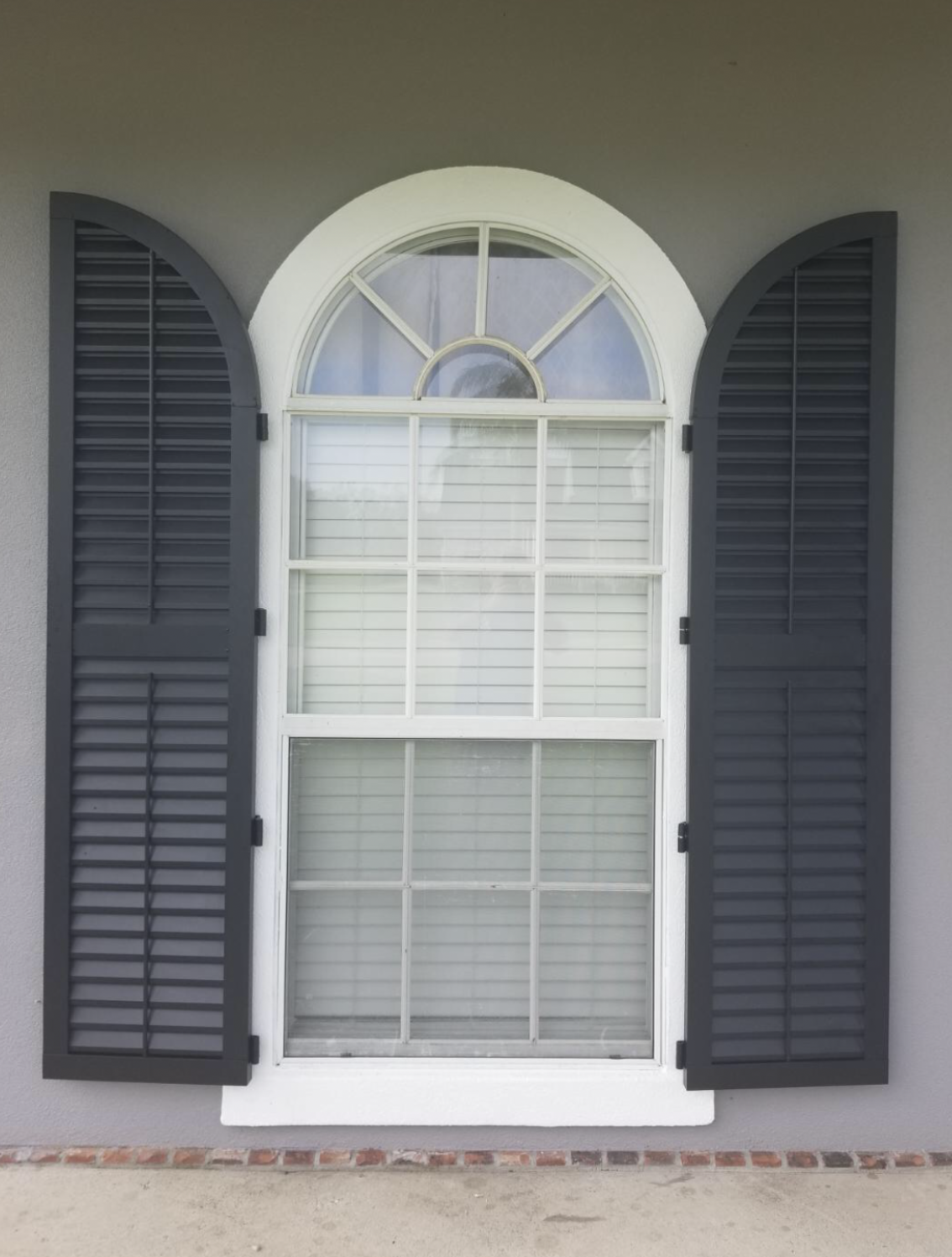 A white window with black shutters on it.