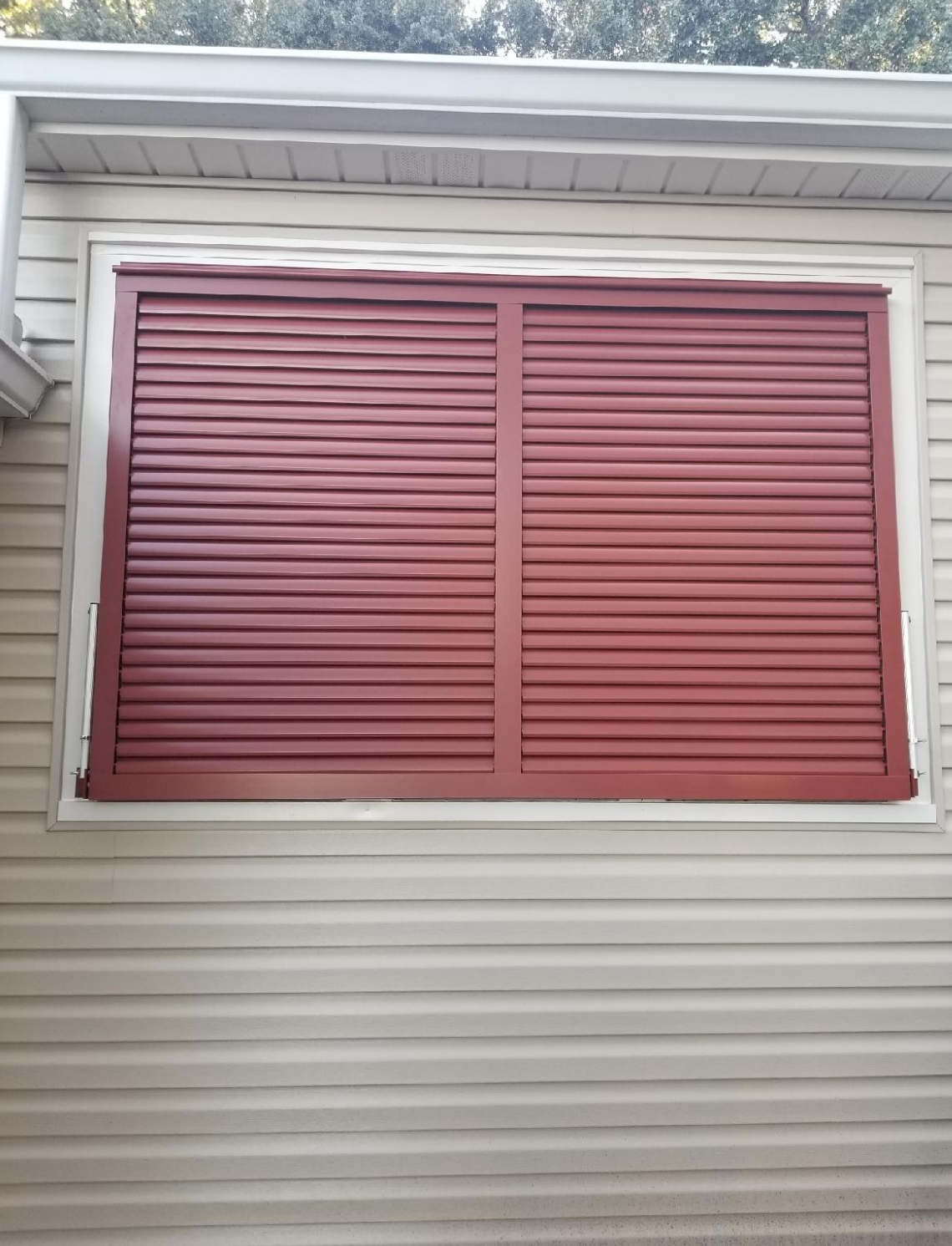 A window with red shutters on the side of a house.