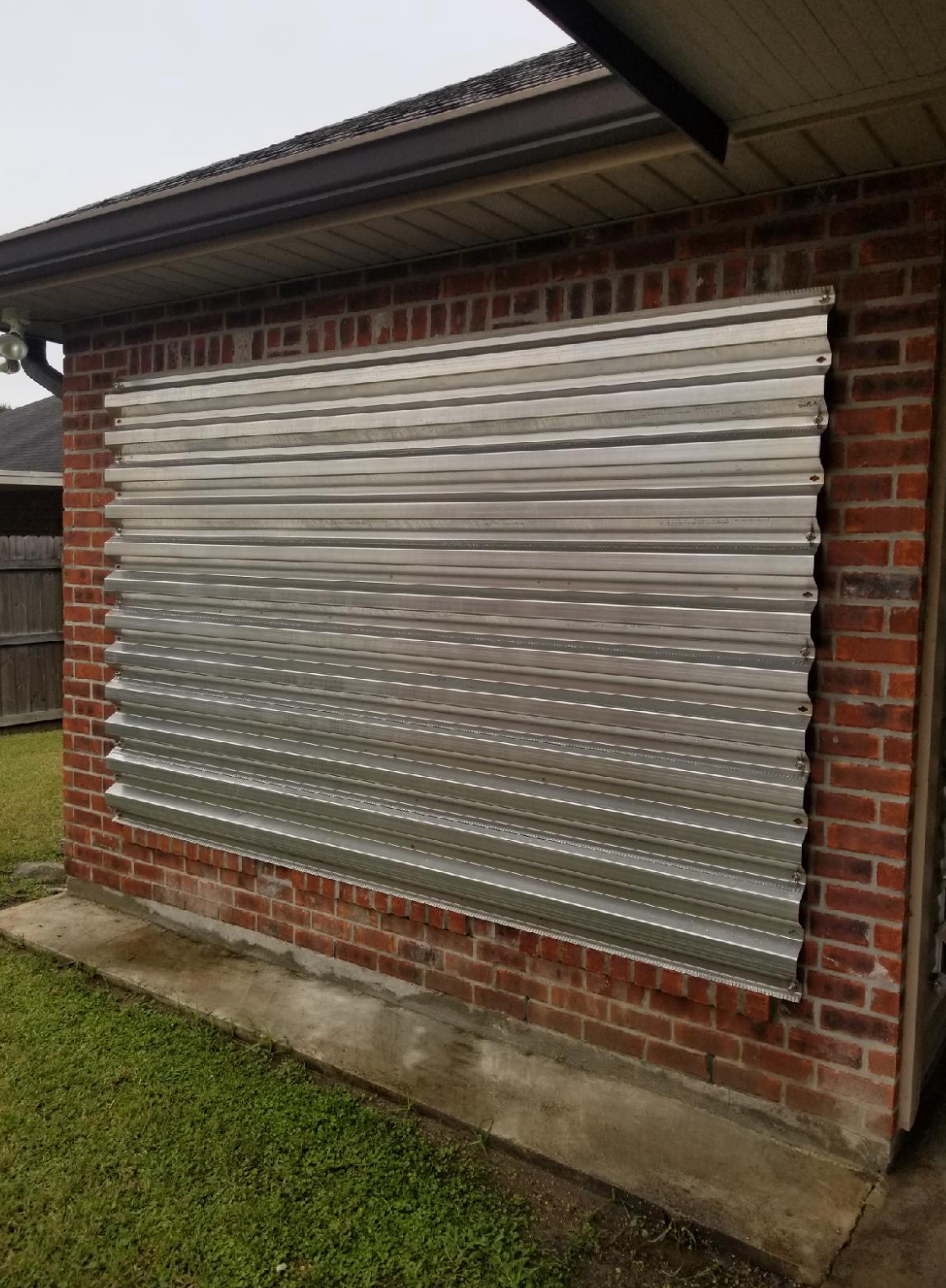 A brick wall with a metal shutter on it.