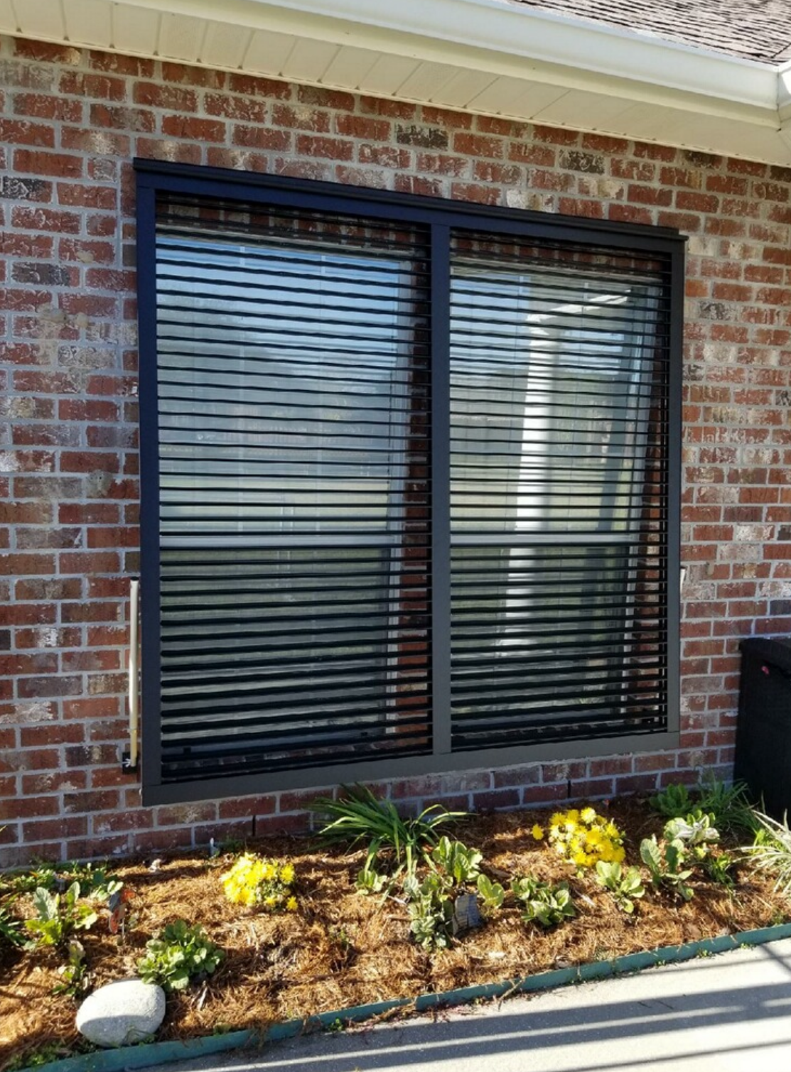 A brick house with a window with blinds on it.