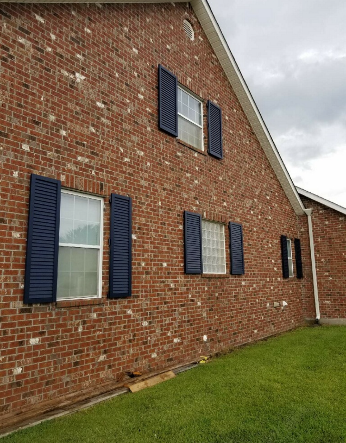 A red brick house with blue shutters on the windows.