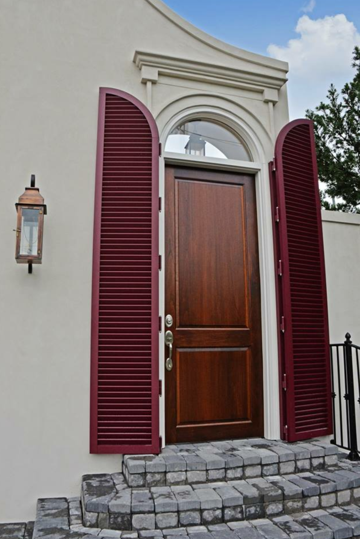 A wooden door with red shutters on a white building.