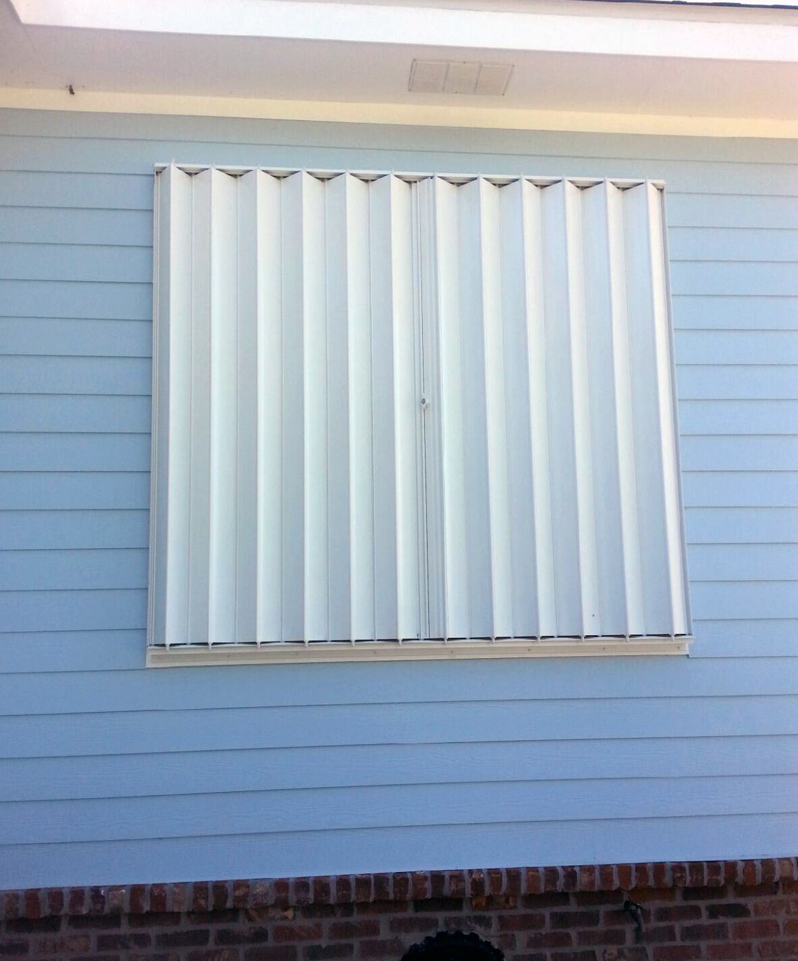 A blue house with a white window with shutters on it.