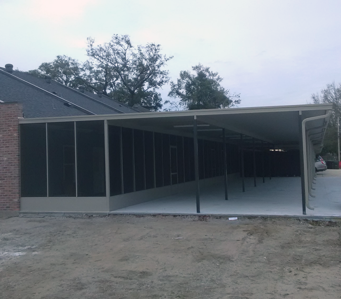 A large covered area with a brick building in the background.
