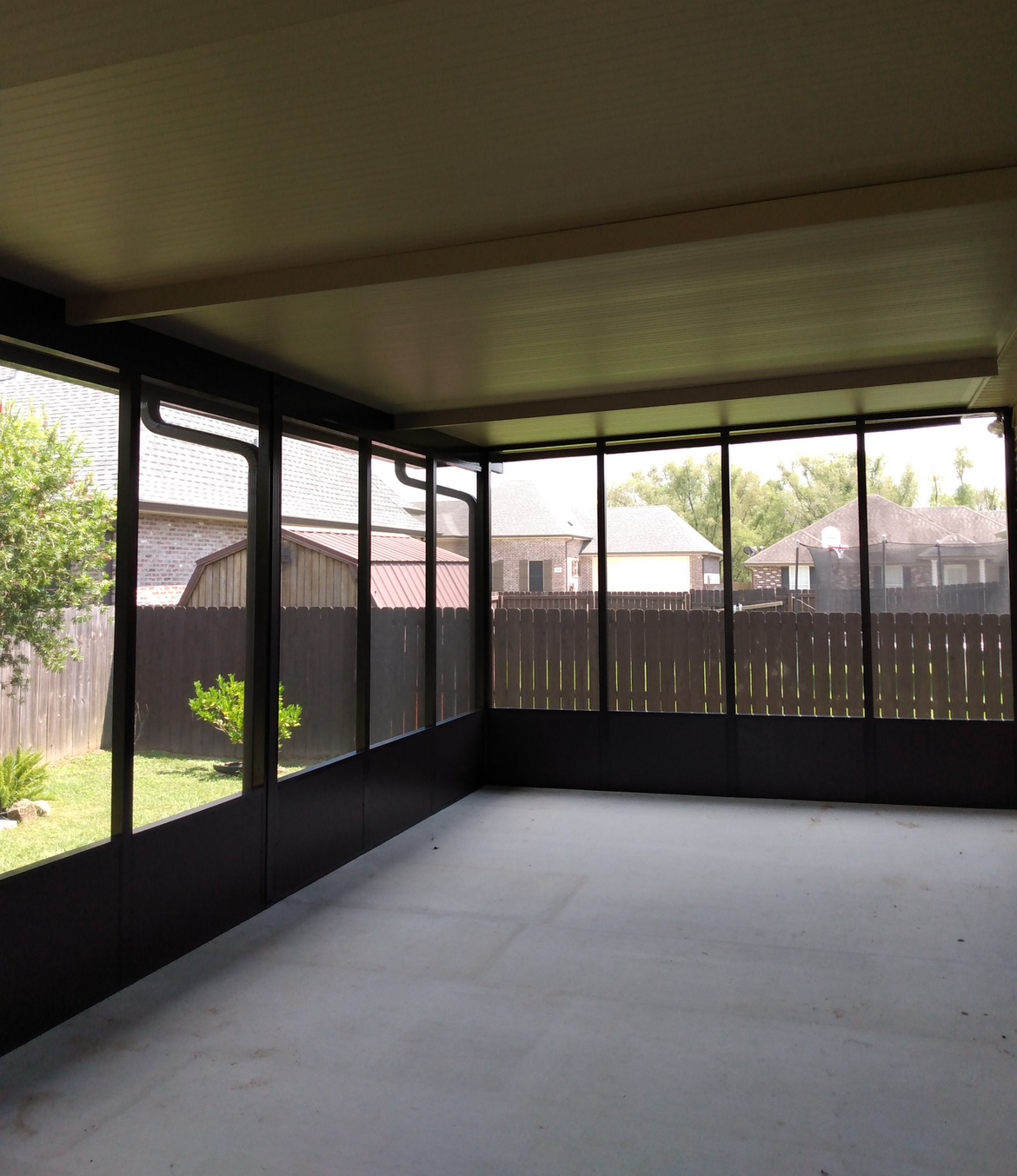 An empty room with lots of windows and a fence in the background.