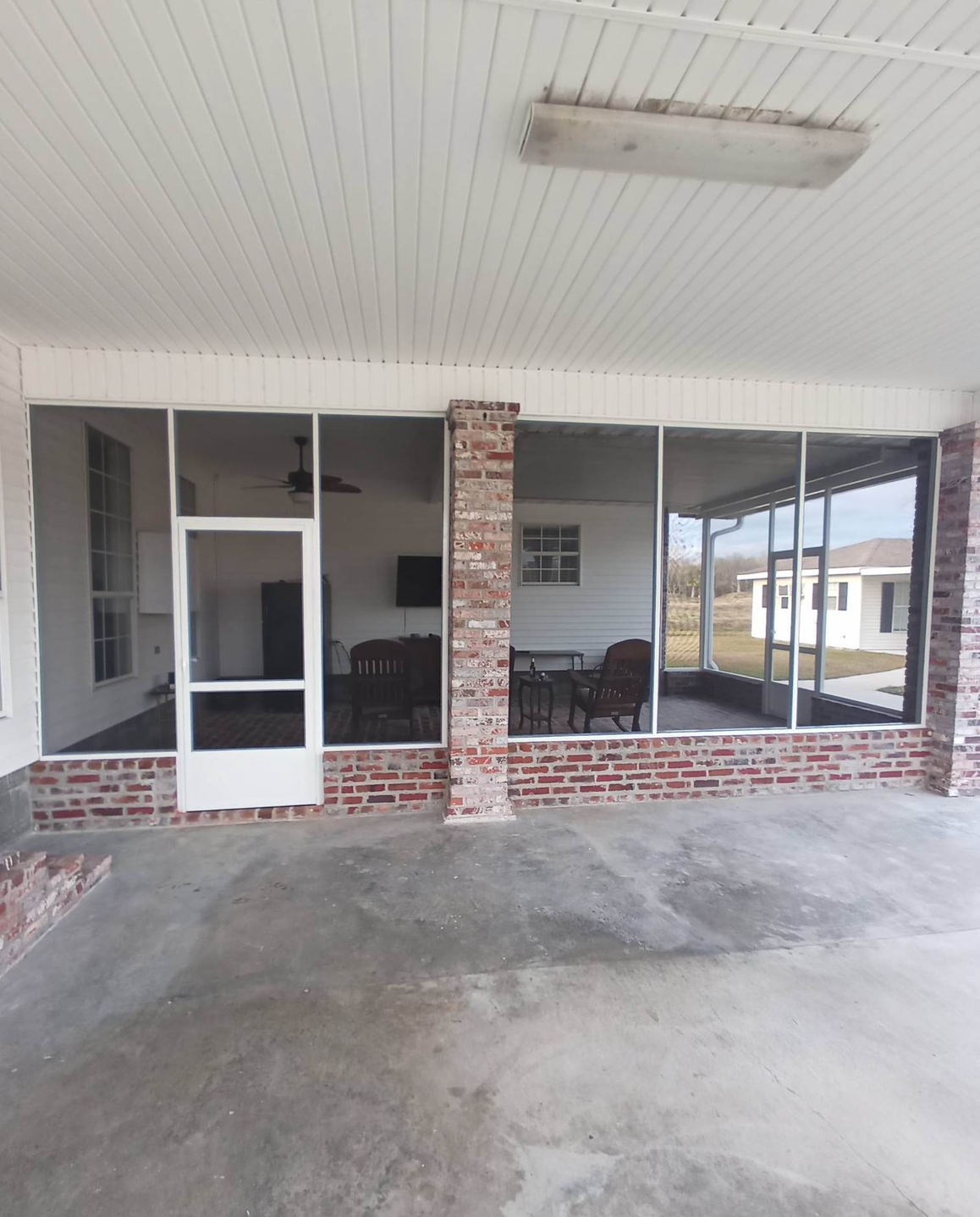 A screened in porch with a brick wall.