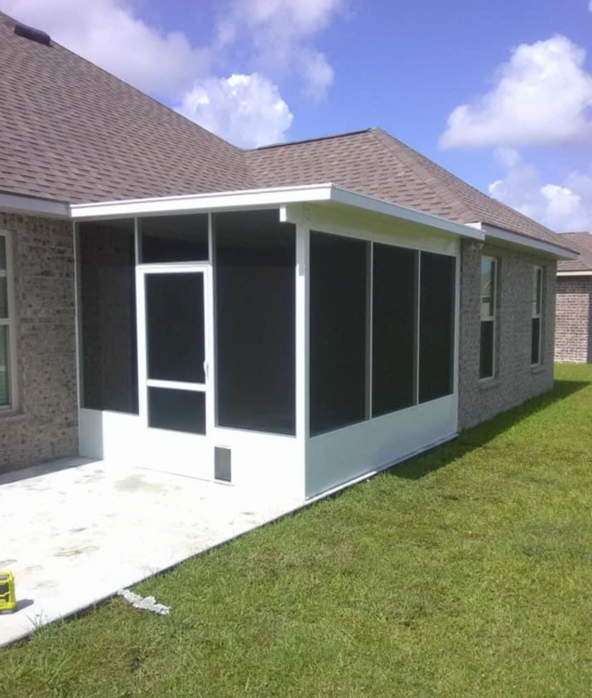 A screened in porch on the side of a house.