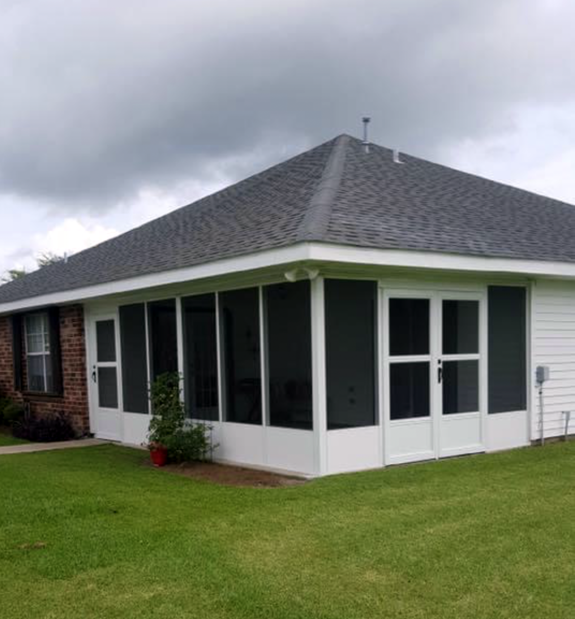 A house with a screened in porch and a gray roof.