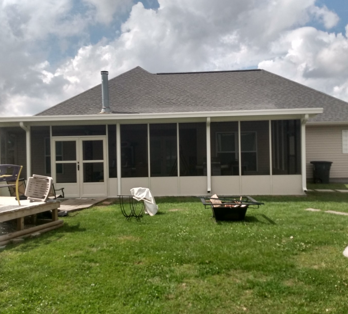 A house with a screened in porch and a fire pit.