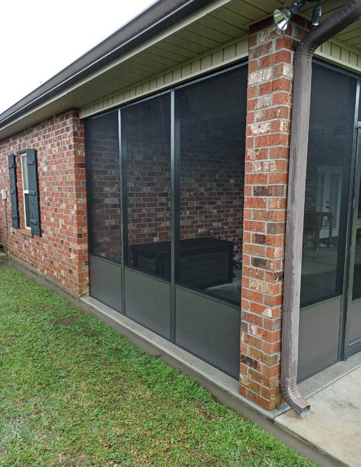 A screened in porch with a brick building in the background.