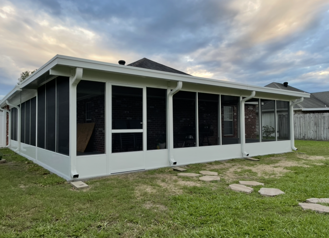 A screened in porch in the backyard of a house.