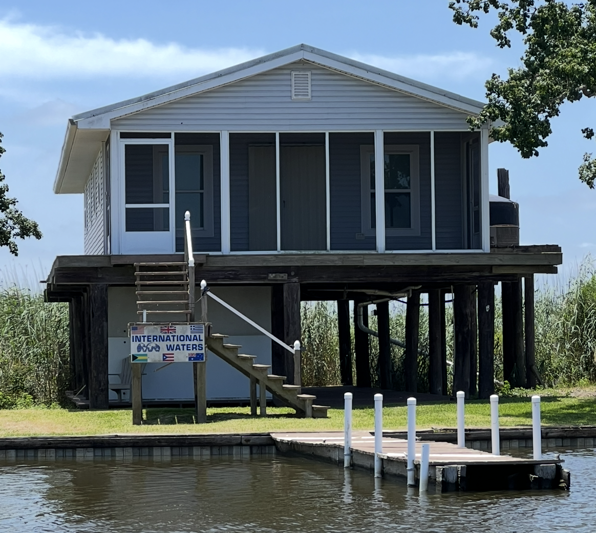A house with a screened in porch sits on stilts over a body of water.