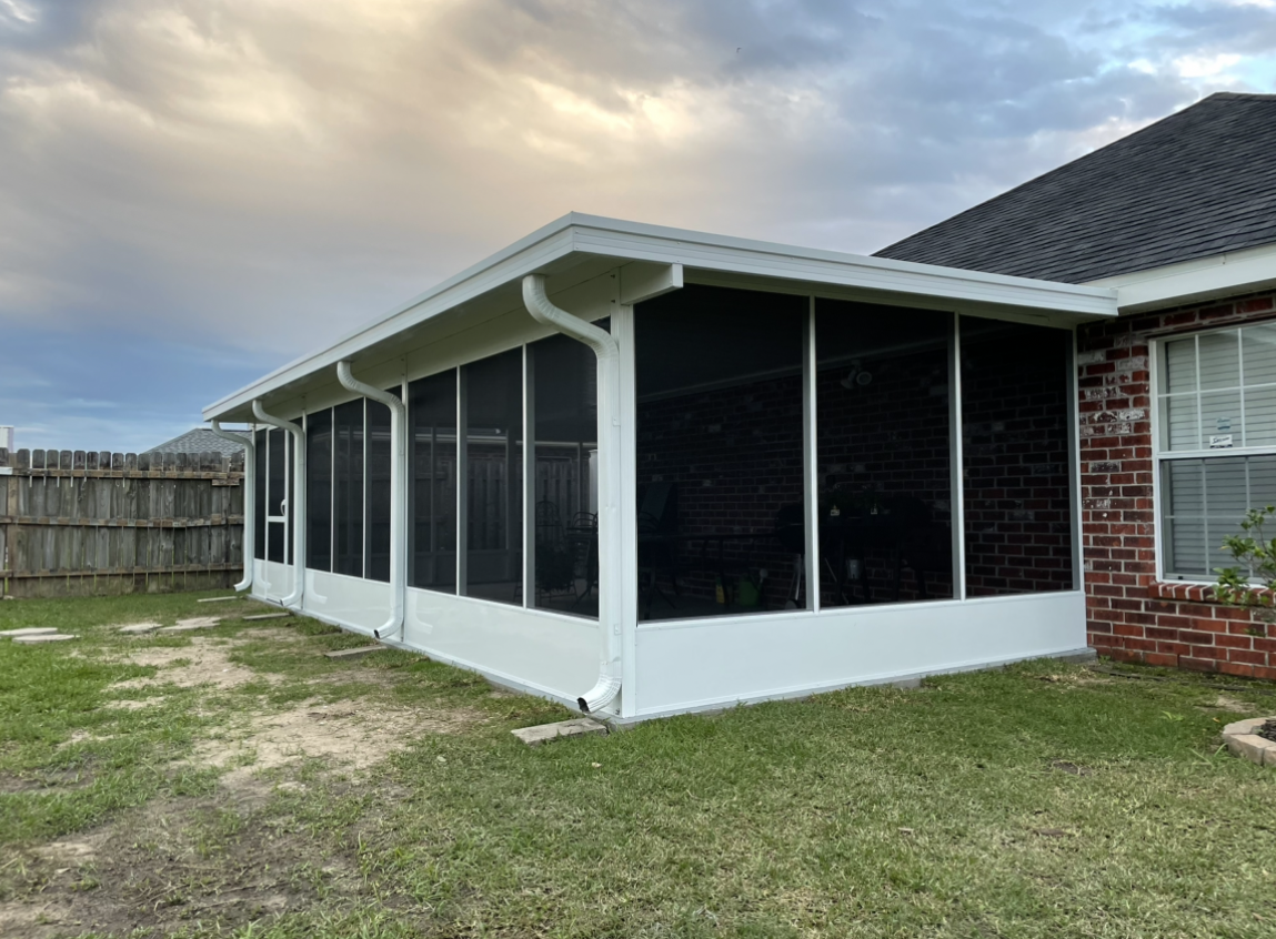 A screened in porch in the backyard of a house.