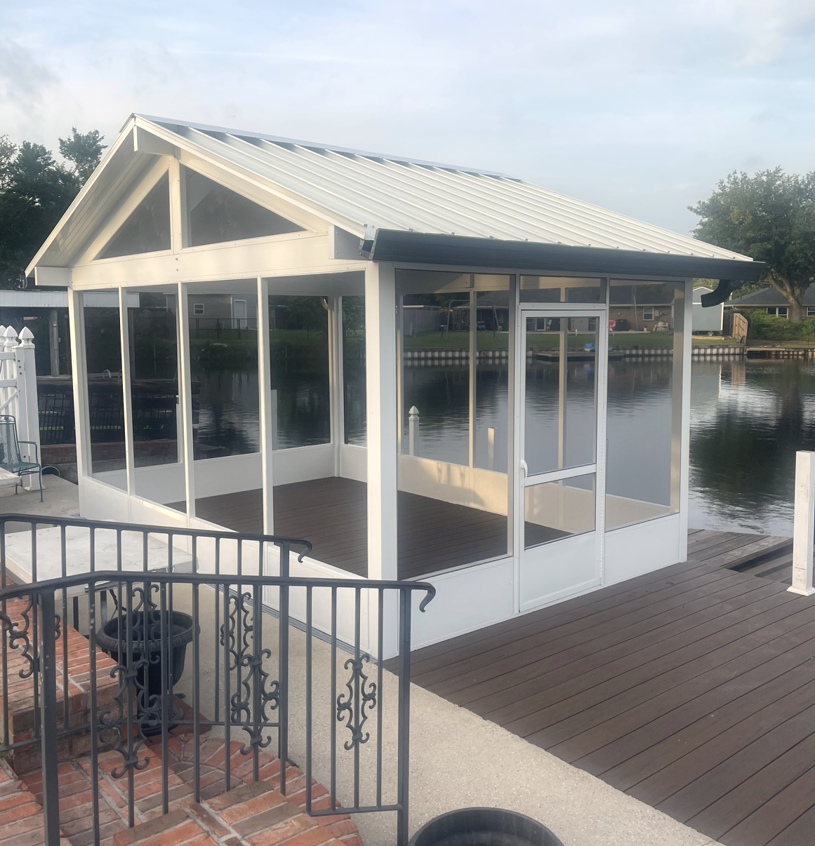 A white gazebo sits on a dock overlooking a body of water.
