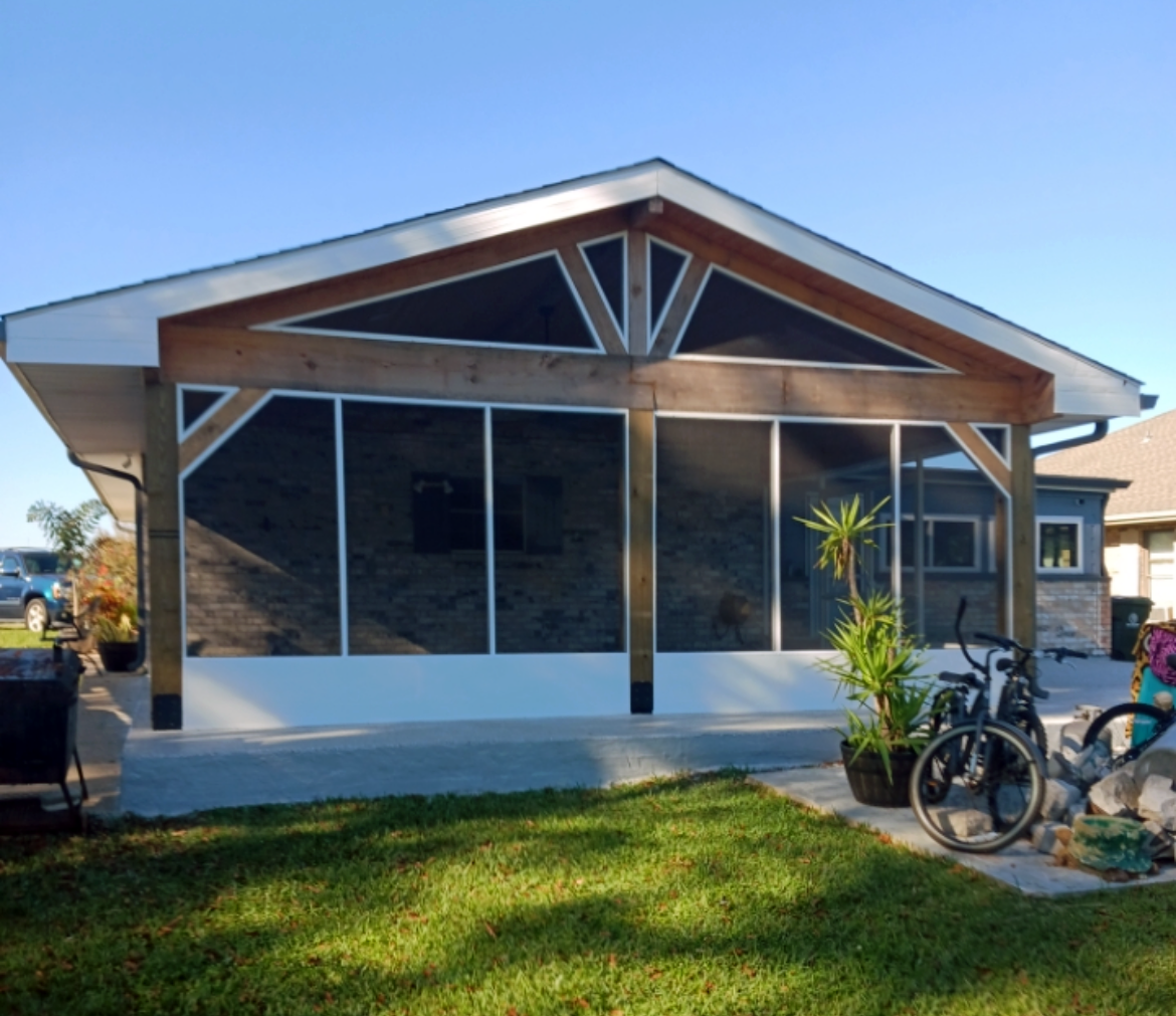 A house with a screened in porch and a bicycle in front of it.